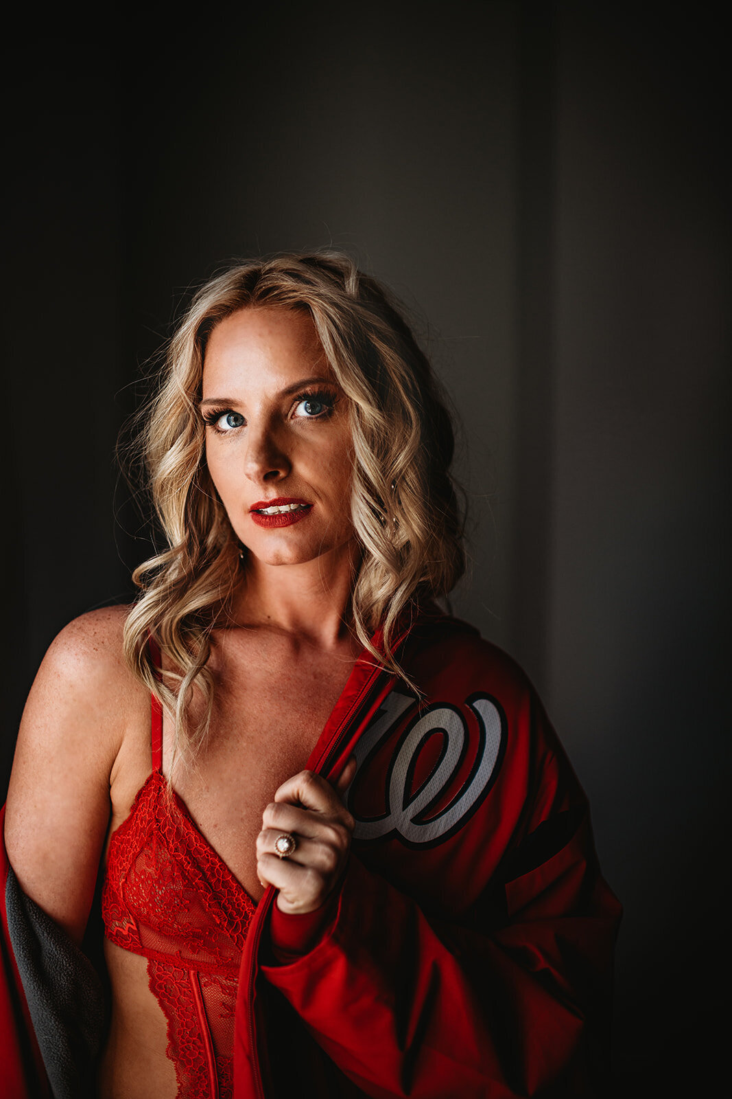 boudoir pictures with woman wearing a red lace bra and a jersery draped over her shoulders