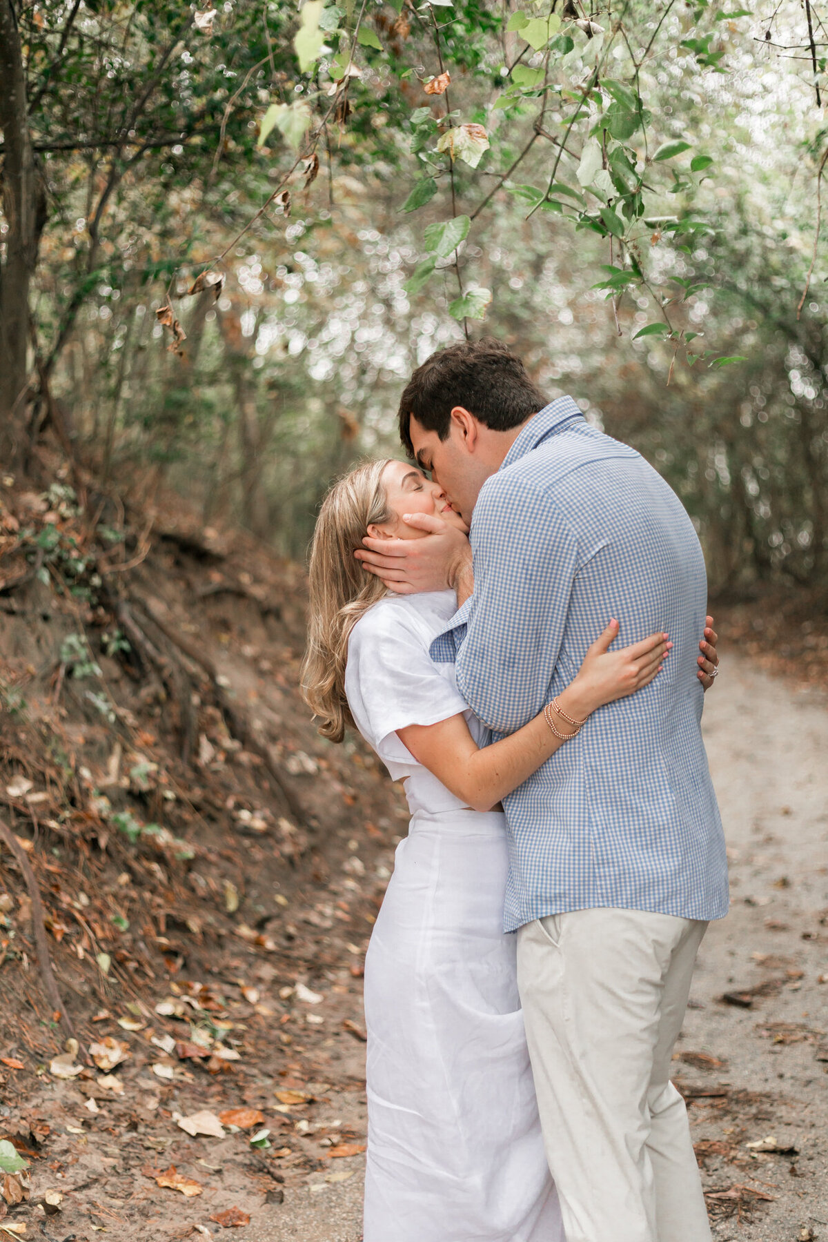 groom grabs bride by cheeks and kisses her for their engagement session