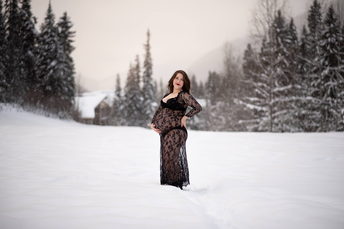 Kamloops Photographer Brittany Danielle captures this gorgeous image of a pregnant woman in the snow. She wears a long black lace dress with her hand on her back, looking off into the distance.