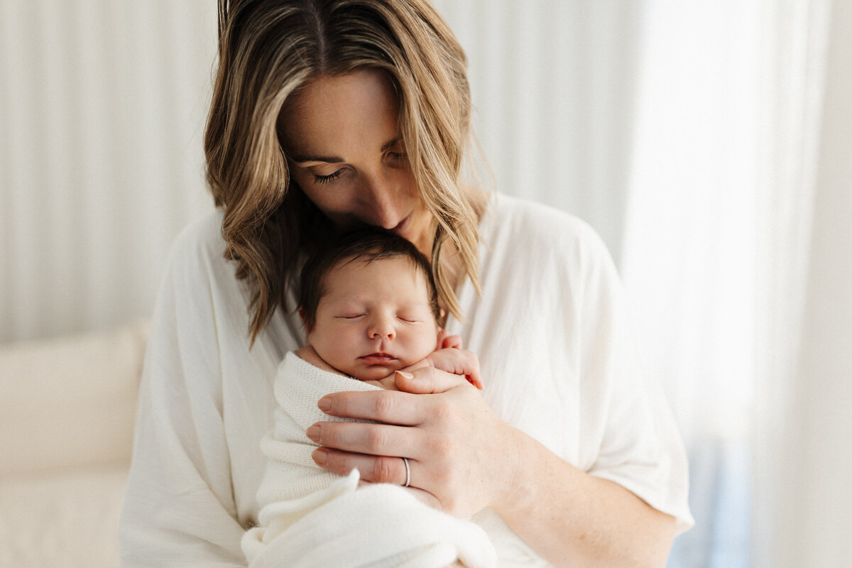 A mother holding her newborn baby during a newborn photoshoot in lucy jane photographys christchurch photography studio