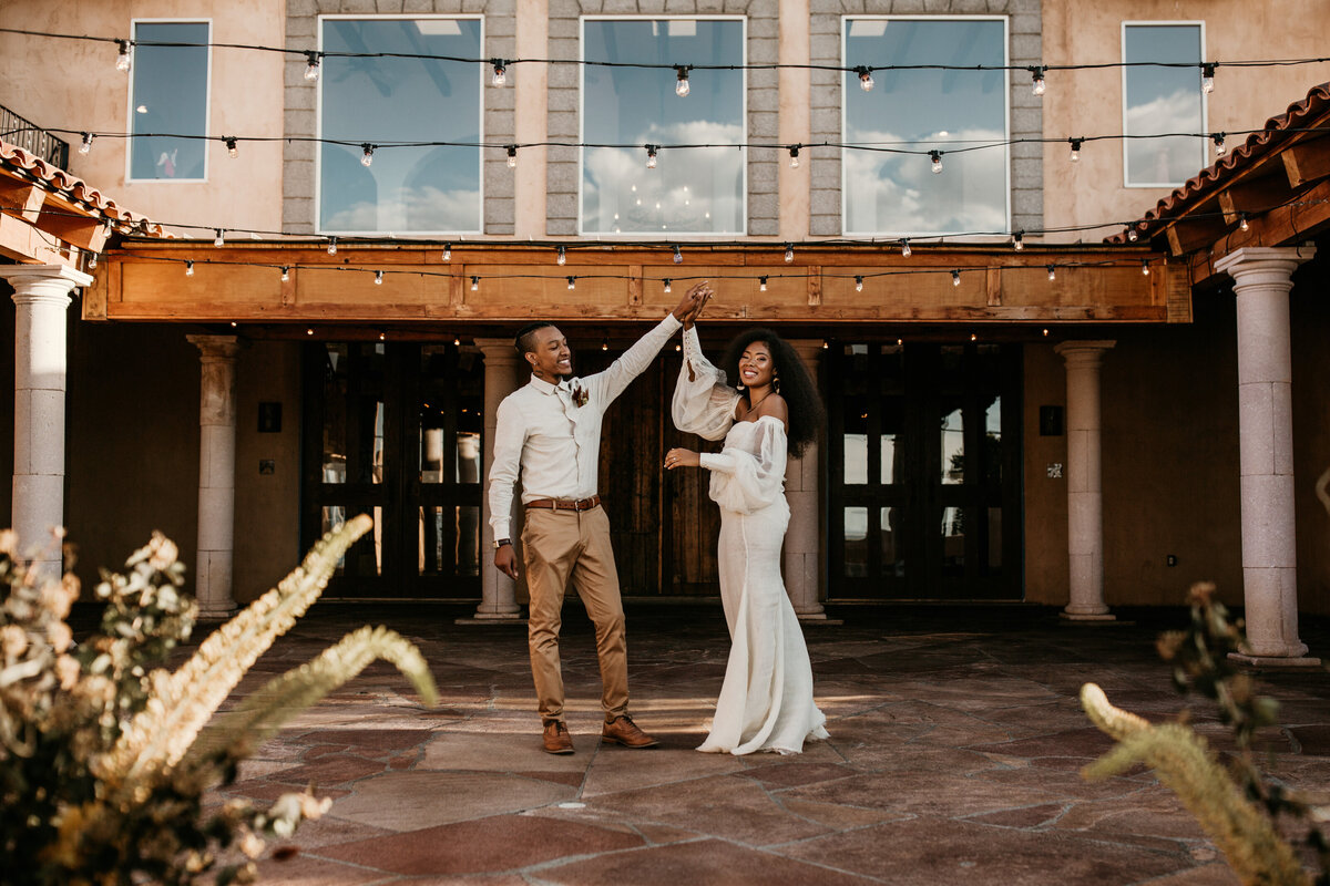 bride and groom dancing together in front of a southwest building