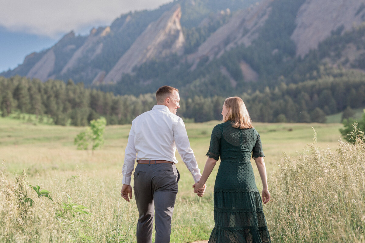 An engaged couple walk together through a field in South Boulder, Colorado