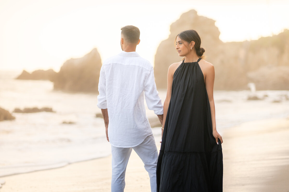 Indian couple eloping at El Matador State Beach in Malibu during low-tide sunset with golden glow and rocky cliff beach.