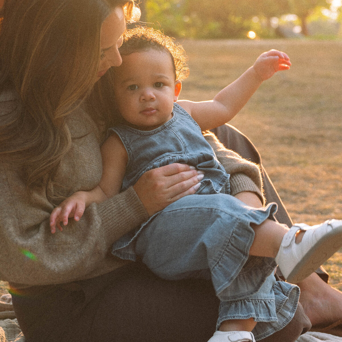 Candid moment of mother holding her toddler in the golden light of an Orange County park.