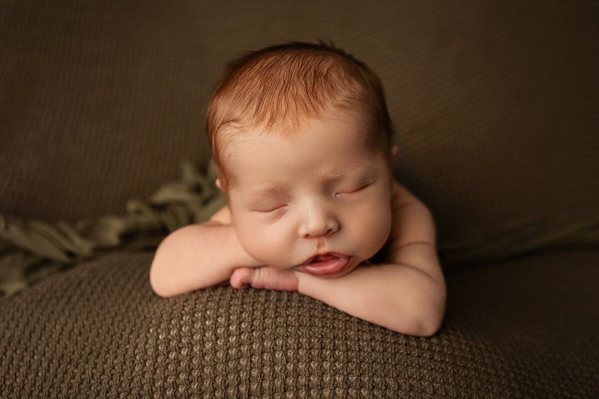 newborn sleeping on tummy with chin on hands