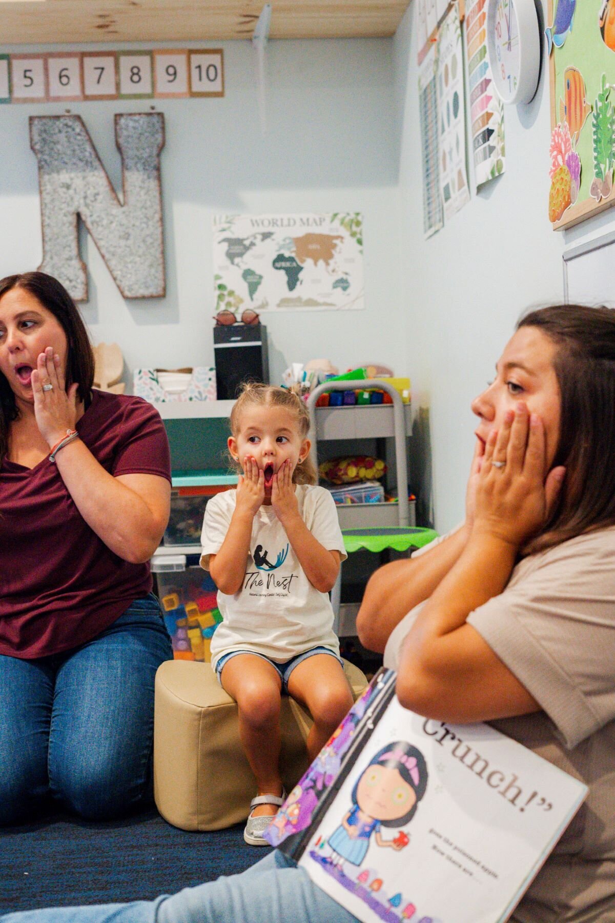 Ms. Brandi, Ms. Mia. and a student making silly faces at story time in the classroom at the Nest, a preschool in Surf City, NC