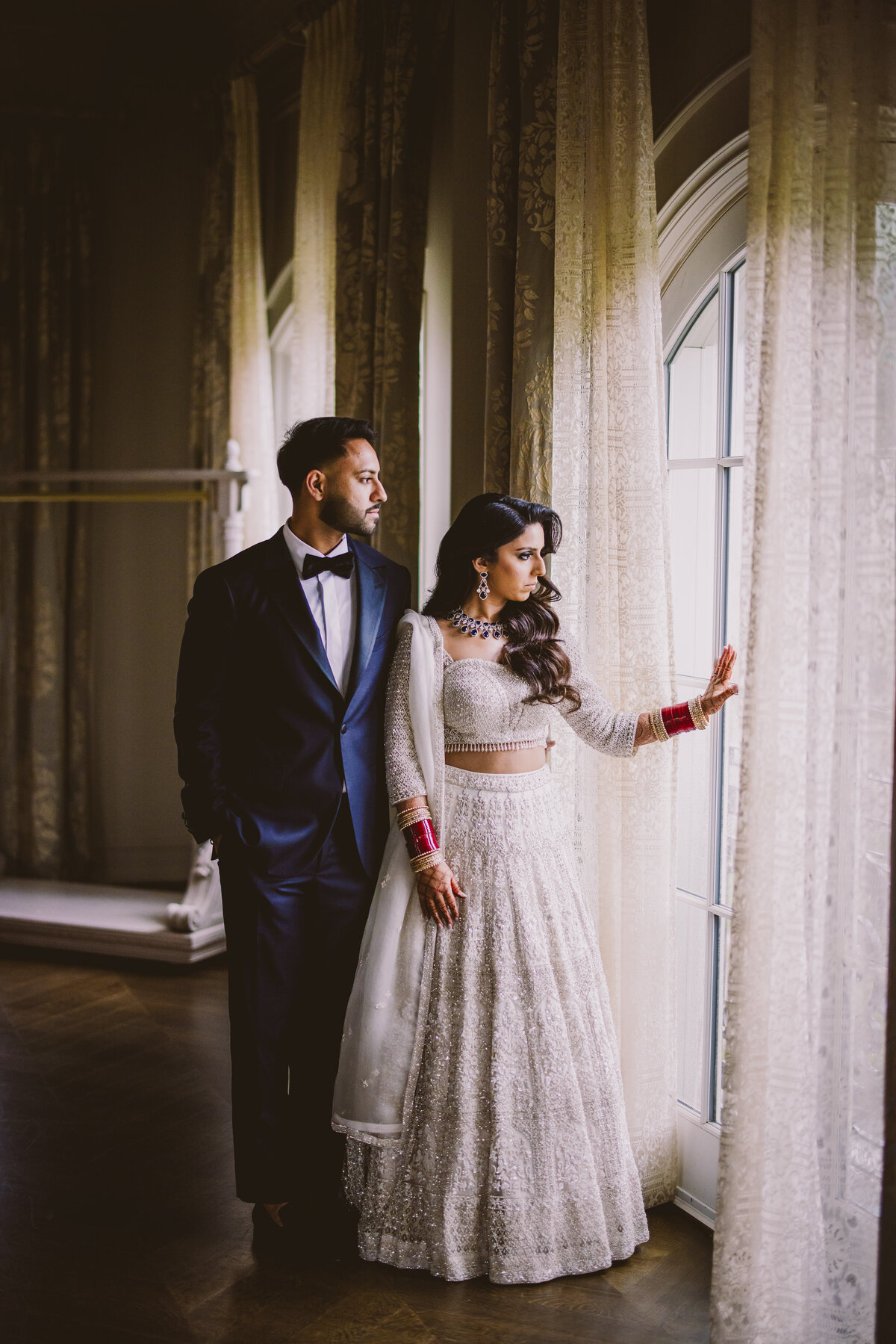 an indian sikh couple look out the window before their wedding reception at the park chateau in nj