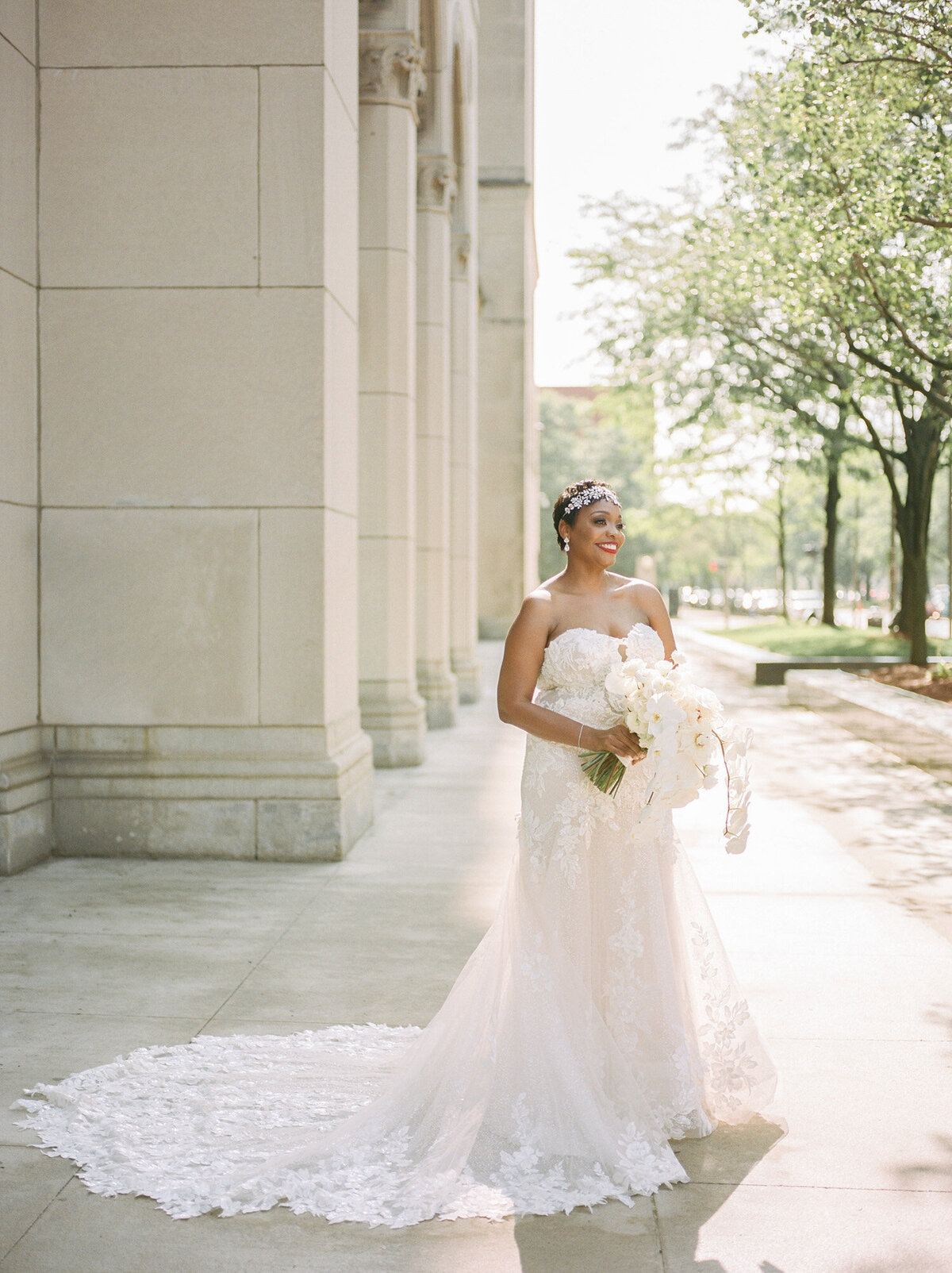 beautiful black bride in luminous light and lace strapless wedding dress, white orchid bouquet