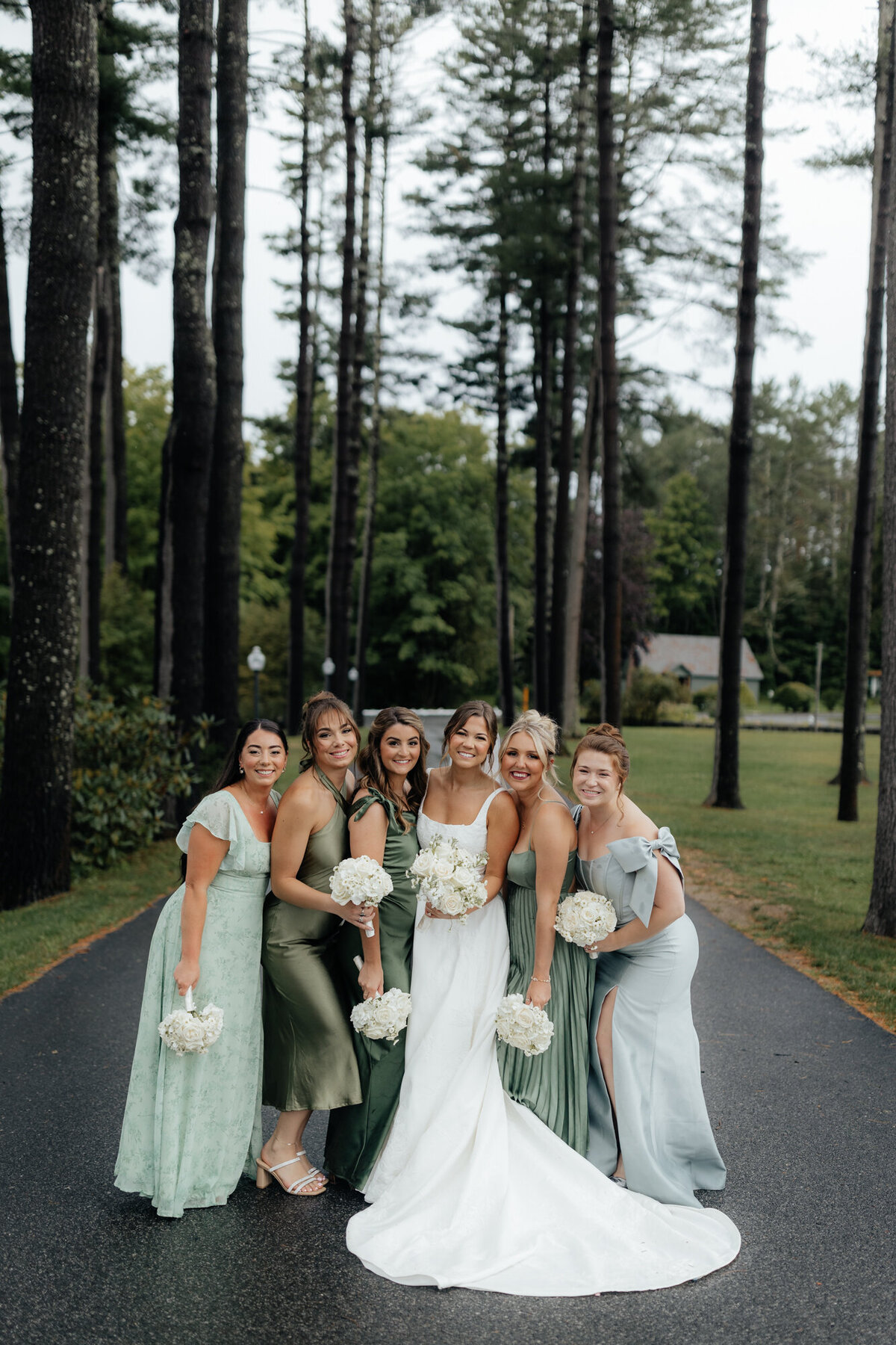 Classic wedding party pose with matching floral arrangements and forest scenery