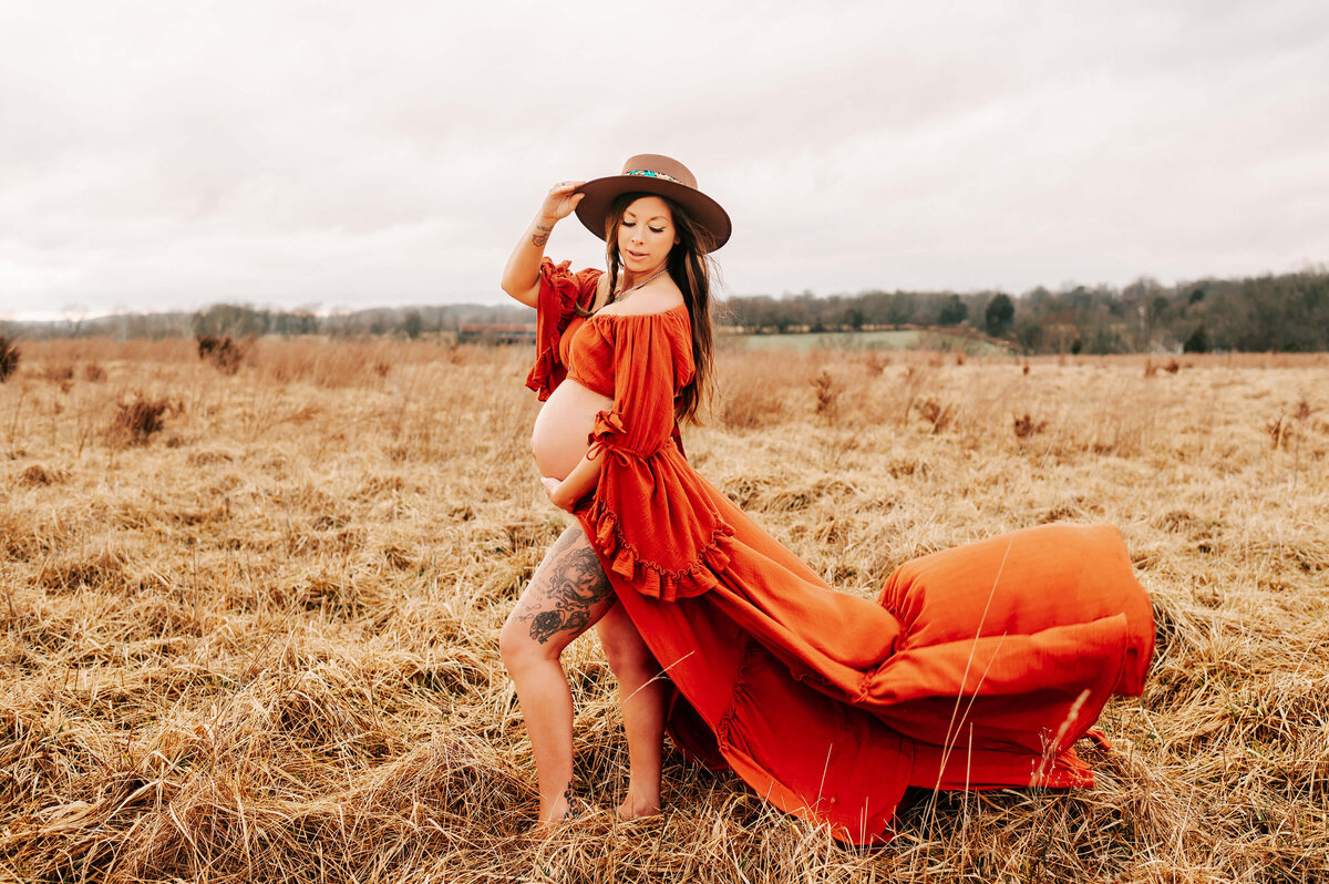 maternity photography of pregnant mom standing in a field at sunset