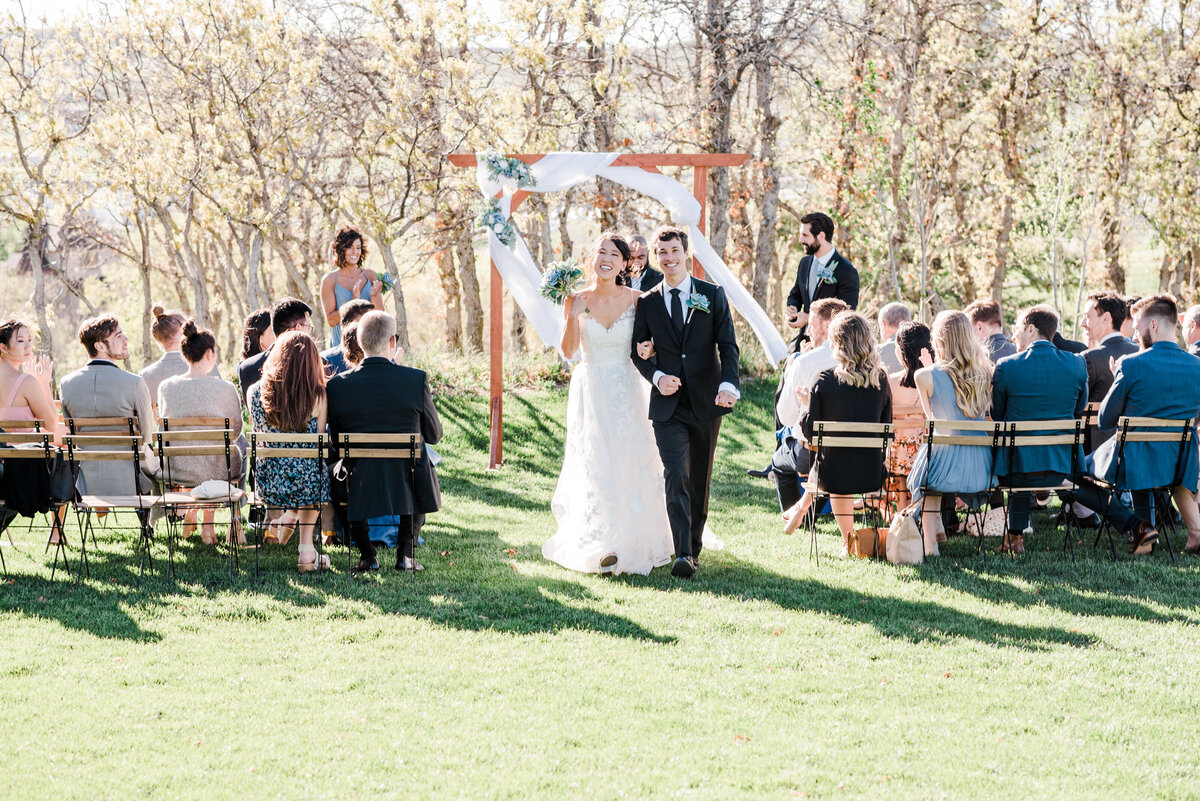 bride and groom exiting their outdoor wedding ceremony in denver as their guests cheer