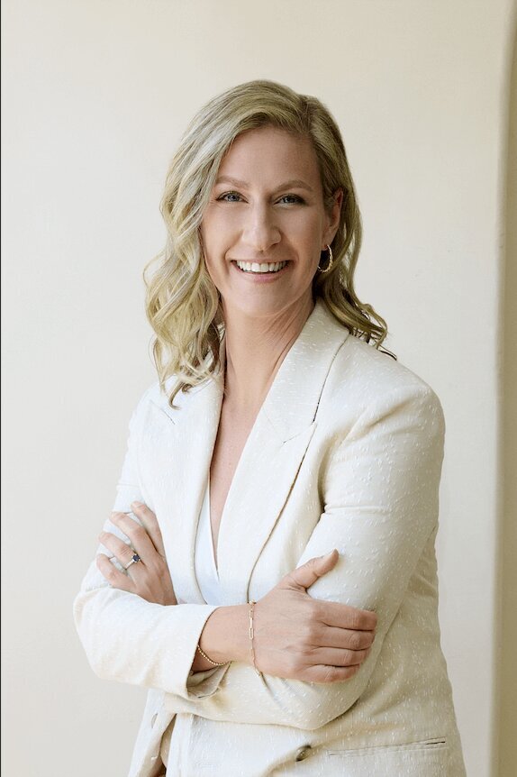woman in a linen suit with a beige backdrop smiling at the camera