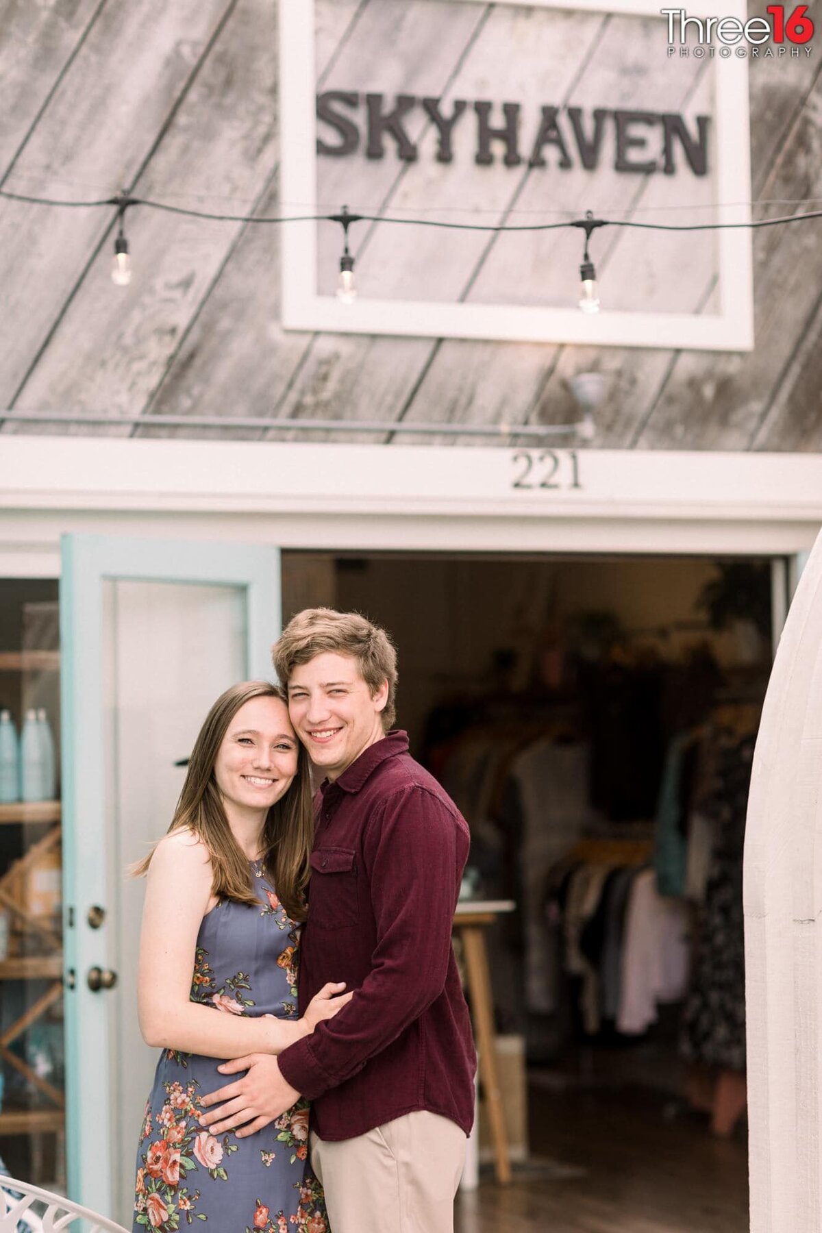 Engaged couple cozy up for pictures in front of a small business in Downtown Balboa Island