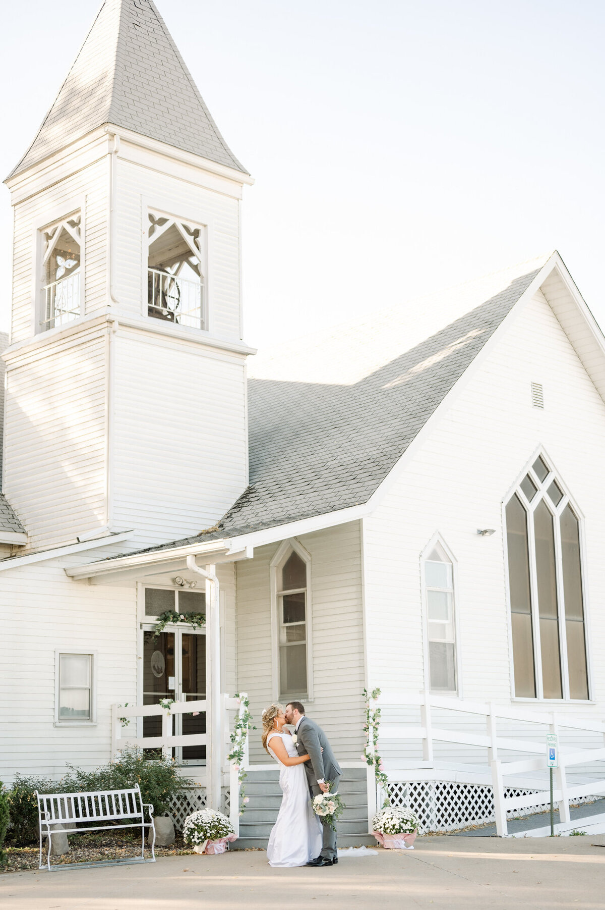 bride and groom kiss which antique white church in the background