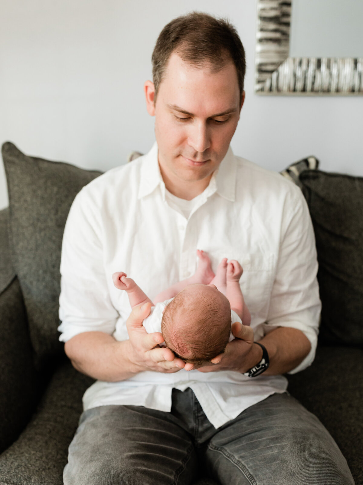 dad holding newborn baby girl in their living room