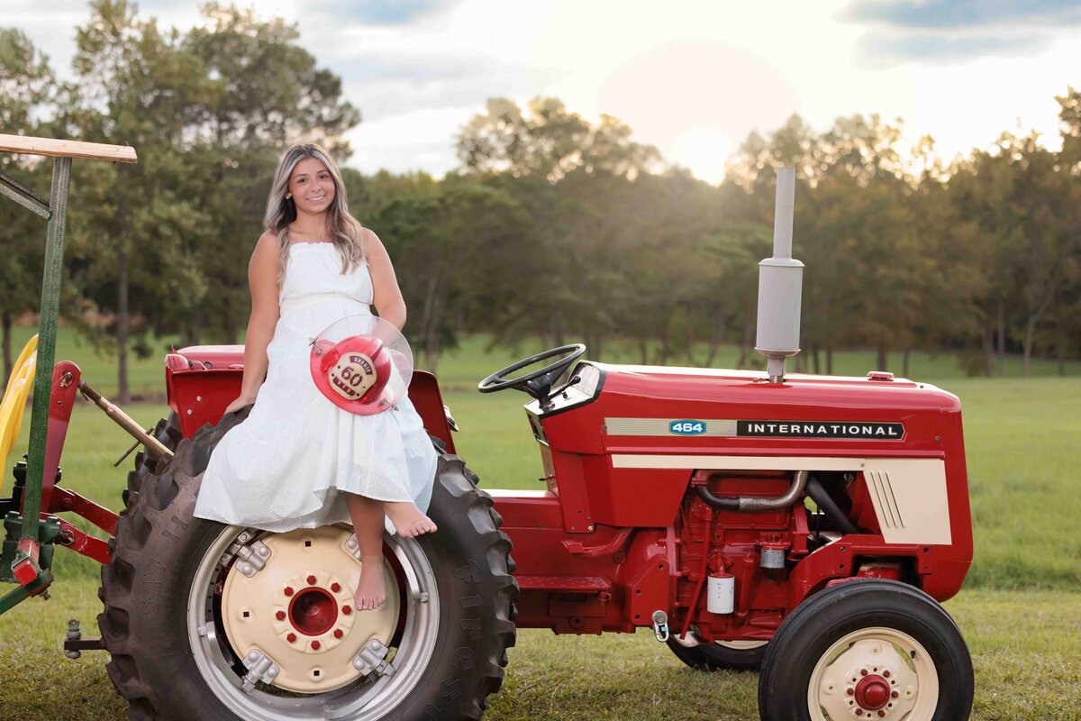High School Senior sitting on a red tractor for senior pictures.