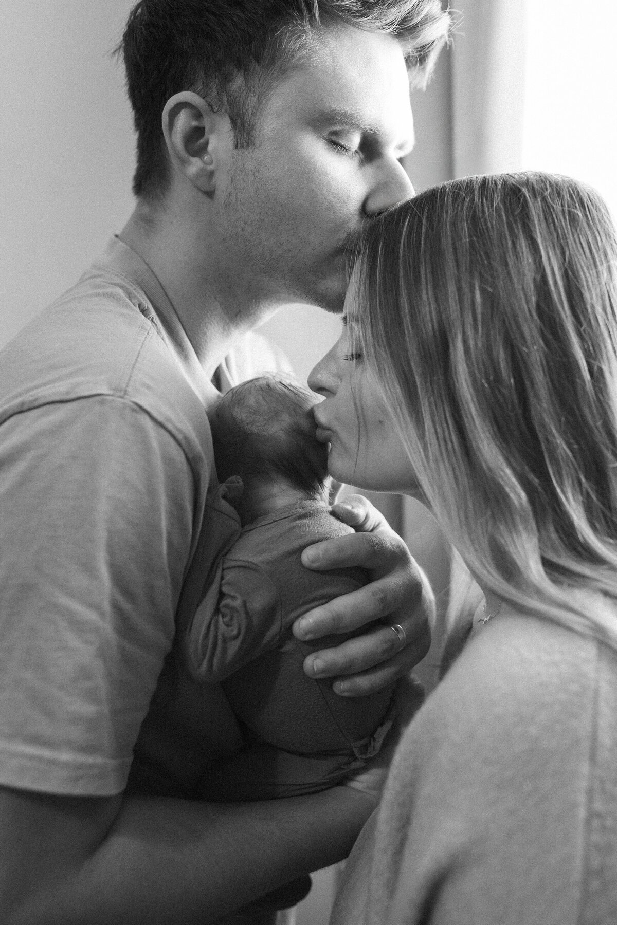 Intimate moment between new parents and newborn during an in-home lifestyle photography session.