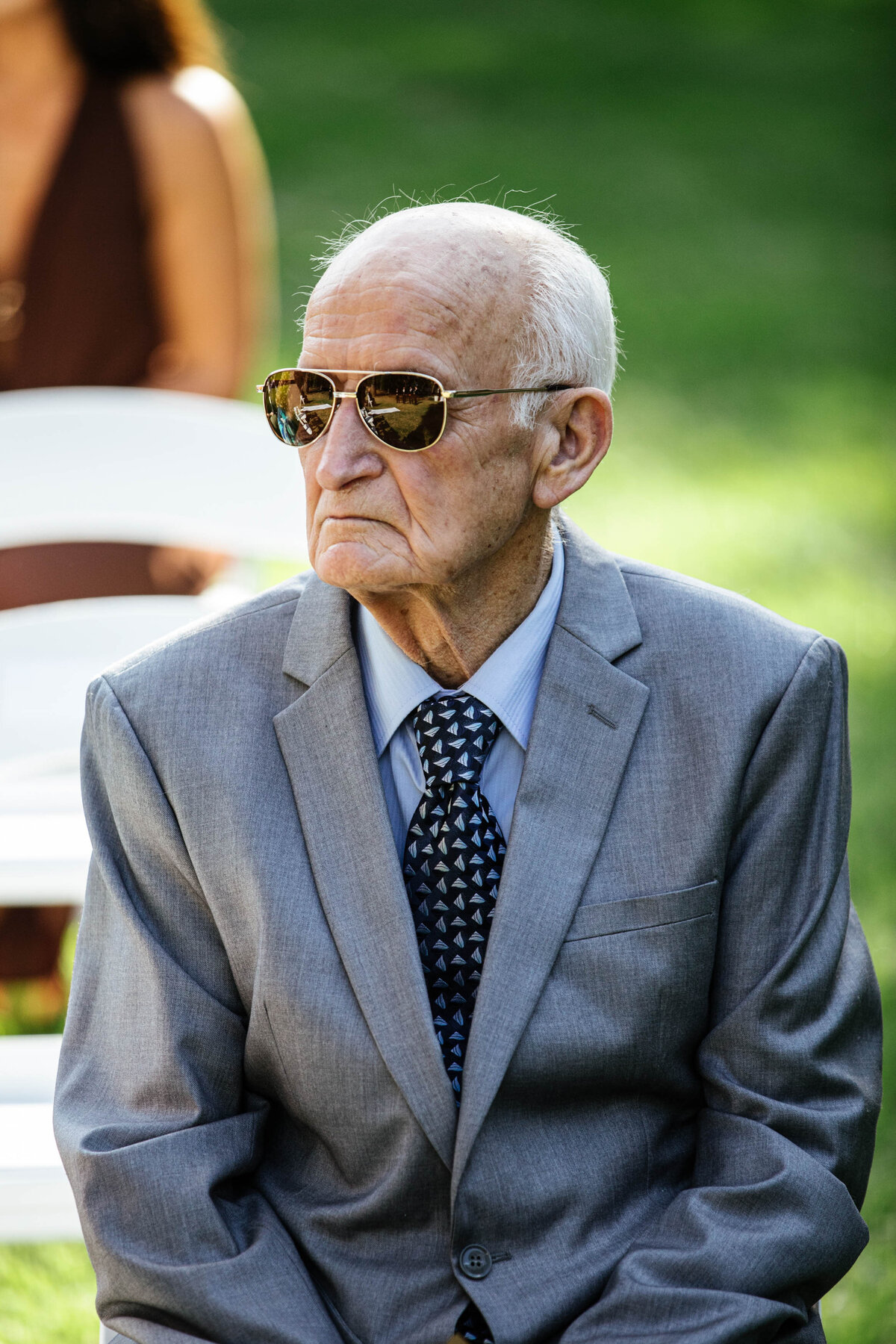 Grandpa is sitting eagerly waiting for the ceremony to start, looking dapper with sunglasses on. 