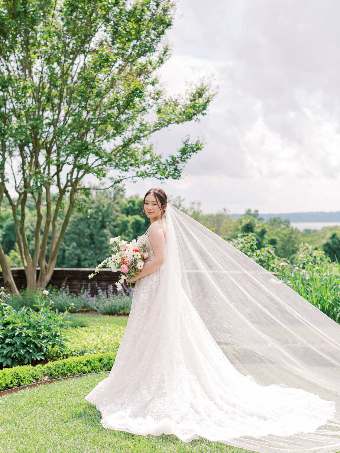 Bride posing outdoors with long veil flowing