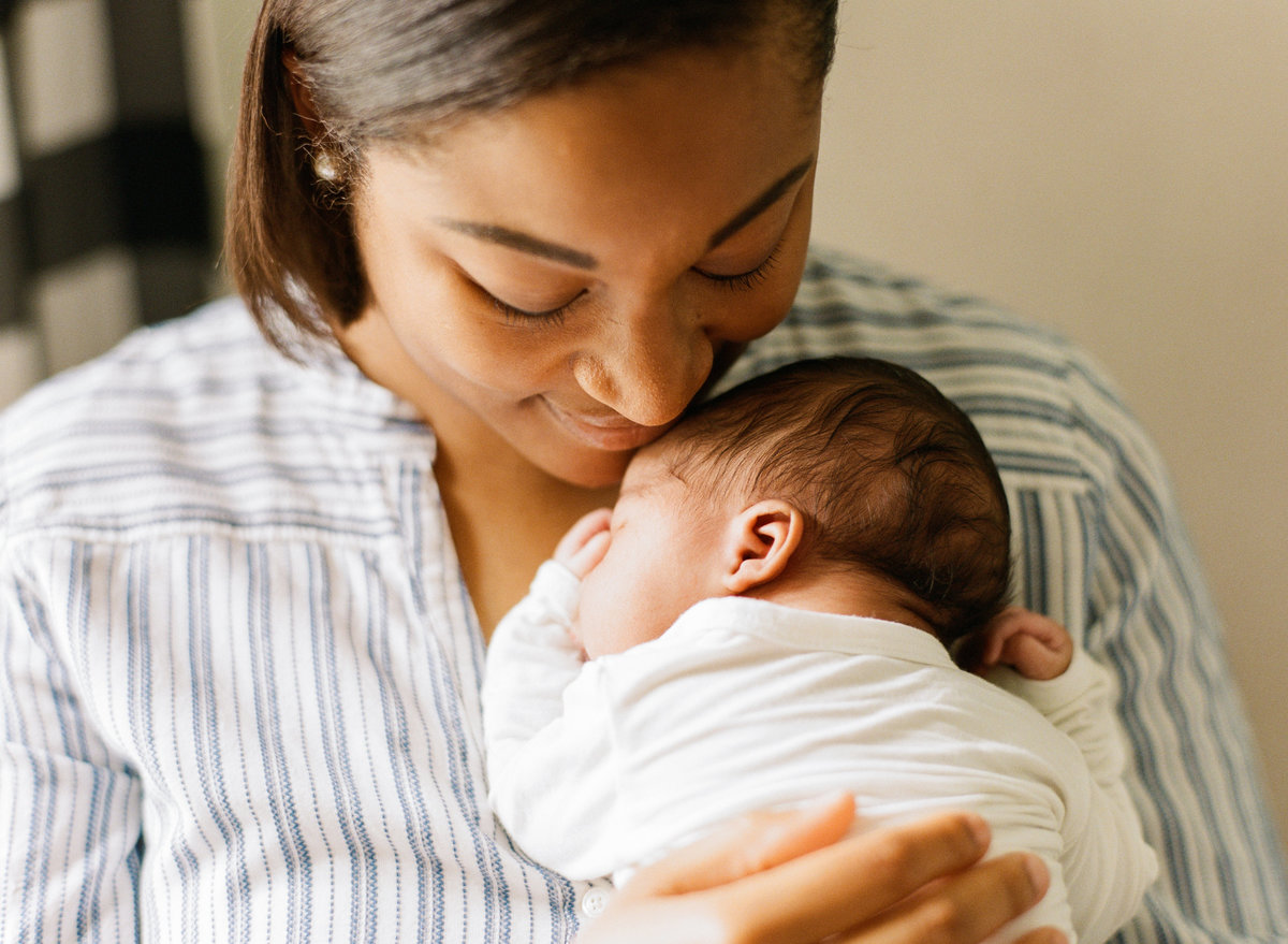 Black mom snuggling her black baby close in a Raleigh newborn photography session. Photographed by newborn photographers Raleigh A.J. Dunlap Photography.