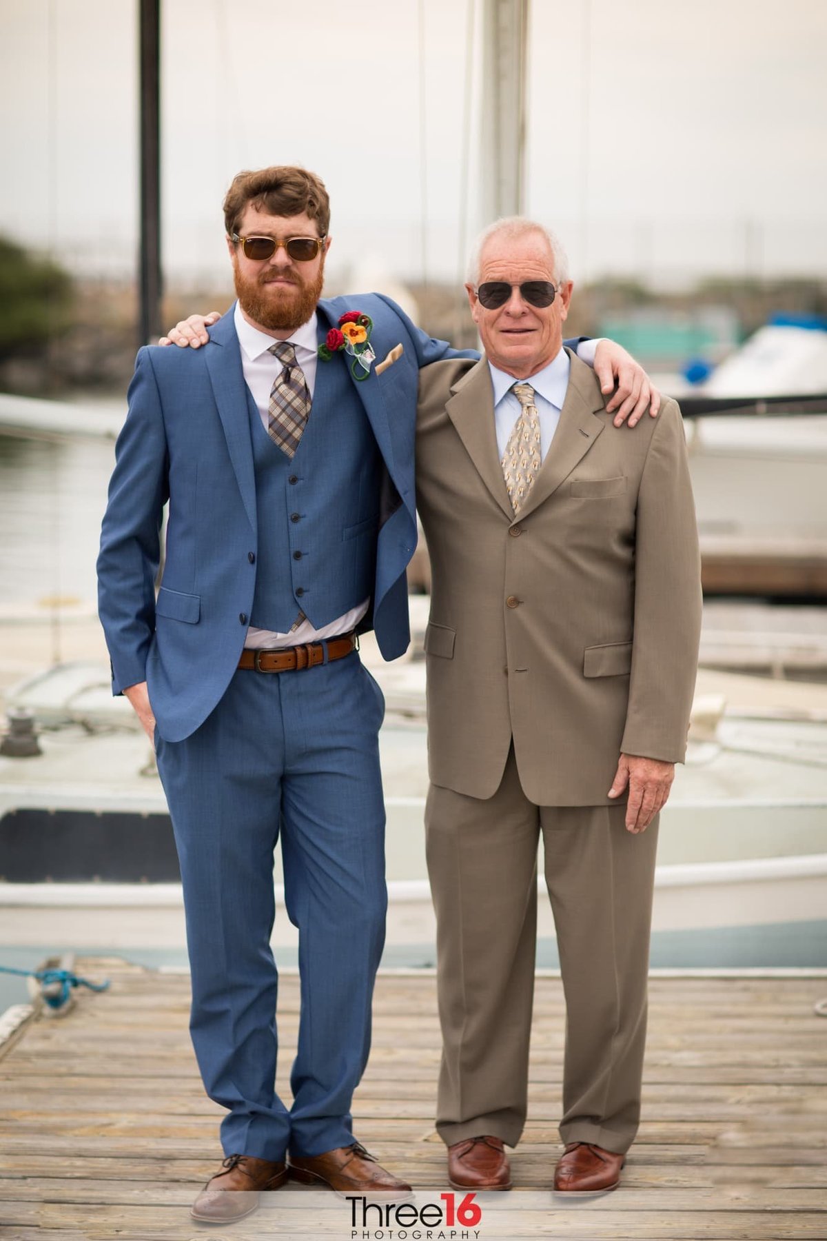 Groom poses with his father on the harbor dock