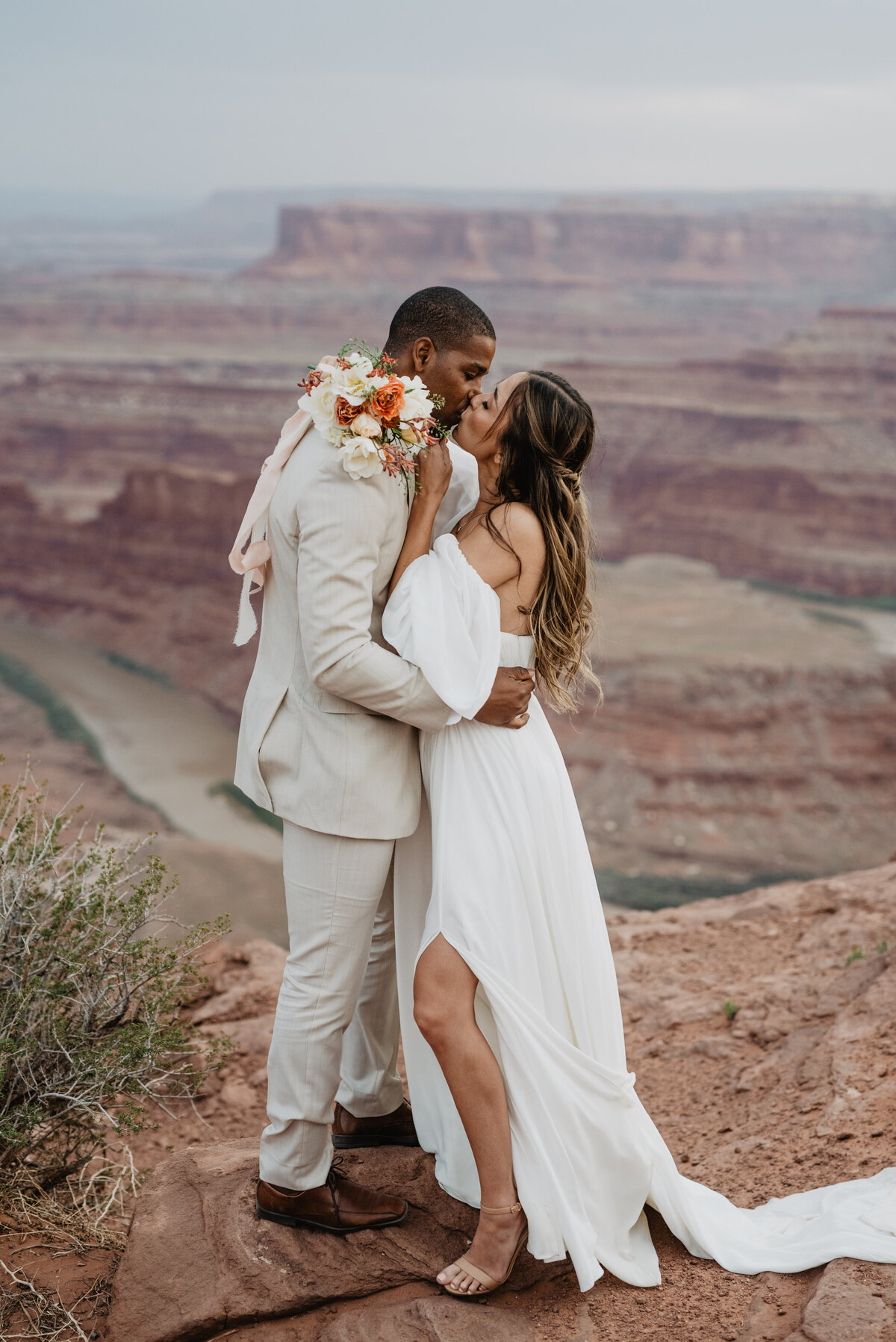 Utah elopement photographer captures couple kissing on top of red rock in Moab