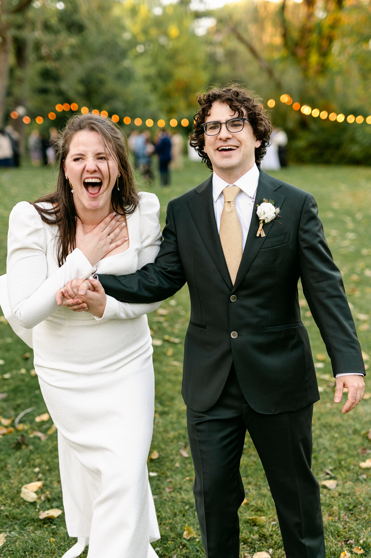 Bride gasping with hand on chest hand in hand with groom