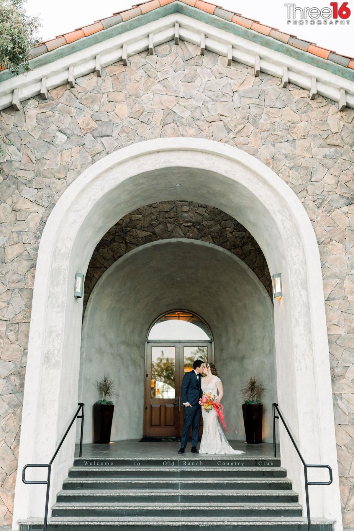 Bride and Groom share a kiss under the large archway entrance