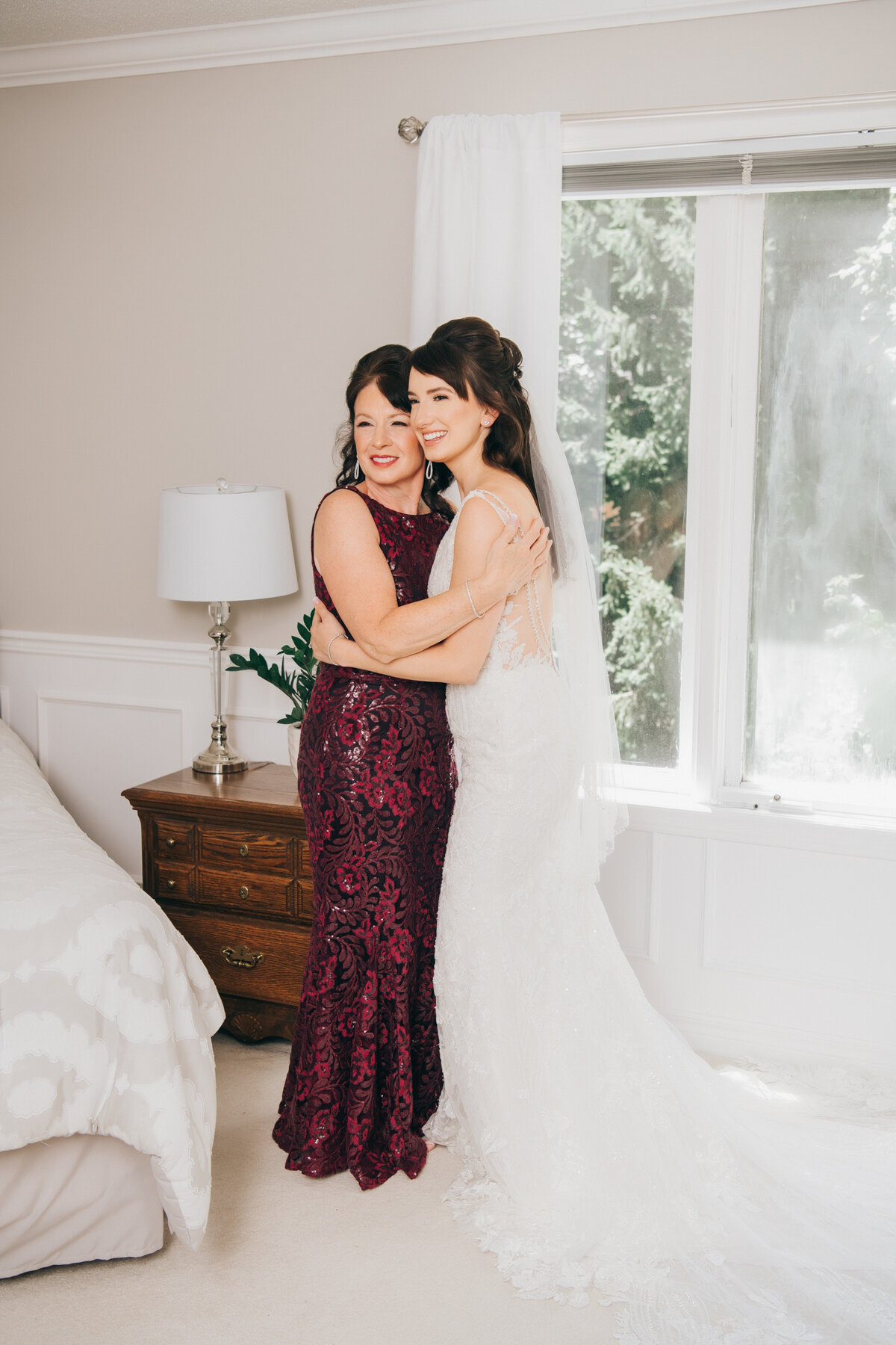 A bride and her mother hugging on the wedding day