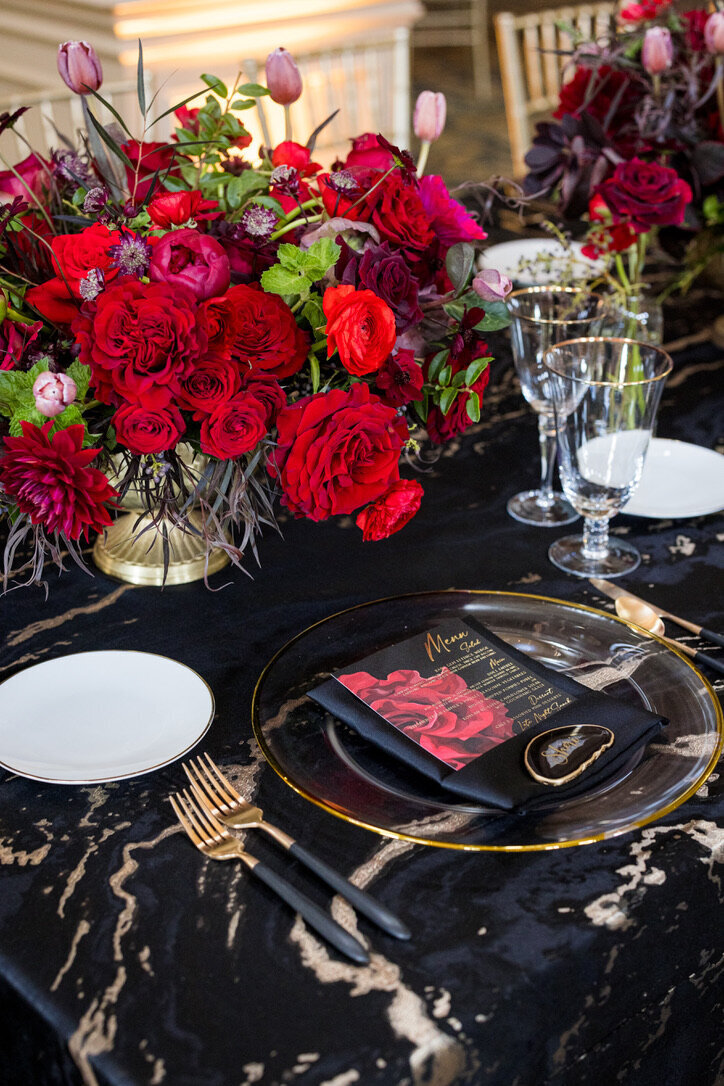 Gold accents, black and gold flatware, red flowers, gold footed dishes, place cards, king tables