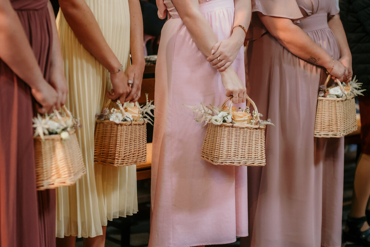 Detailshot of the bridesmaids holding baskets with flowers.