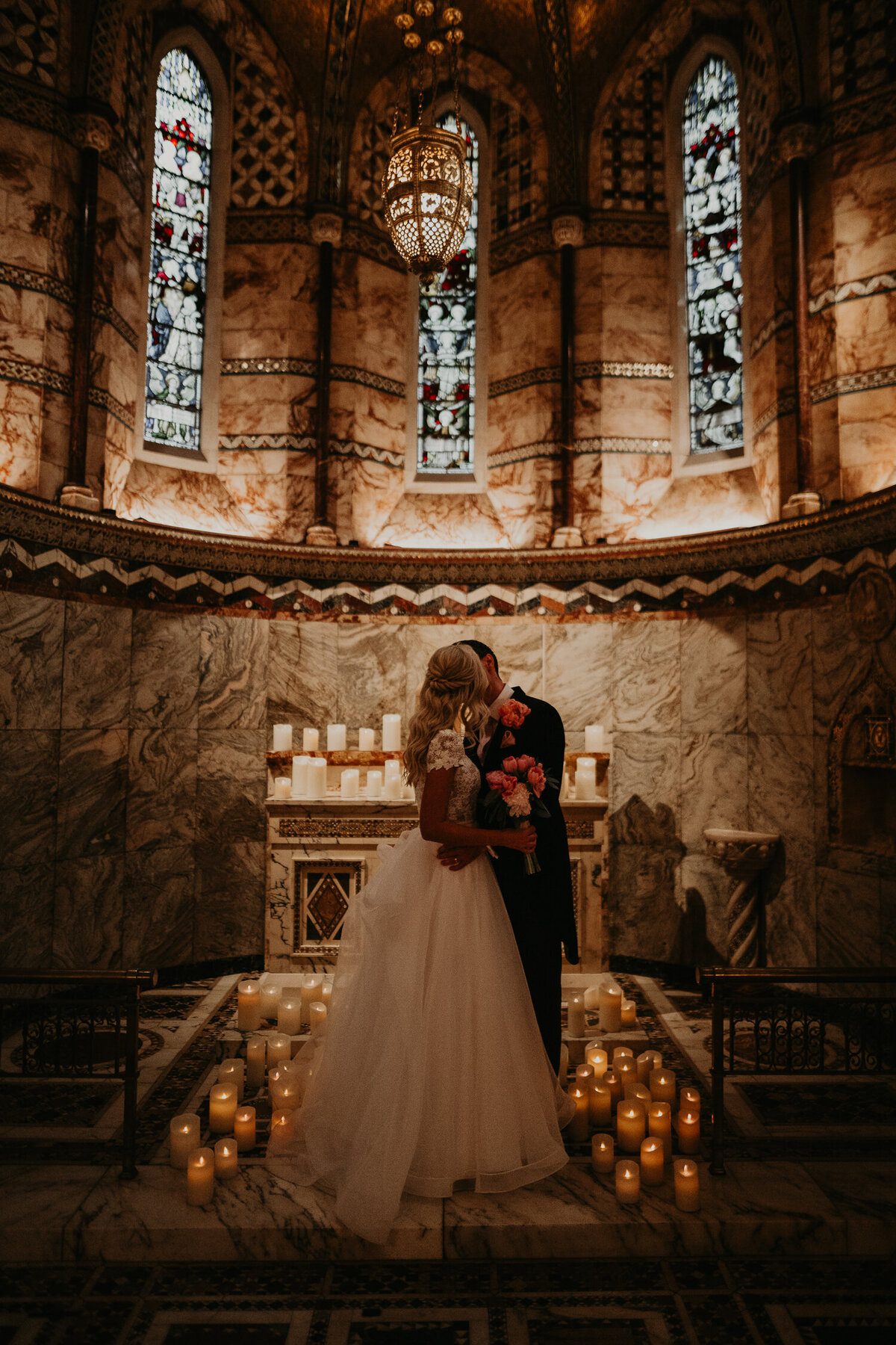 A couple kiss amongst the candles at Fitzrovia Chapel in London.