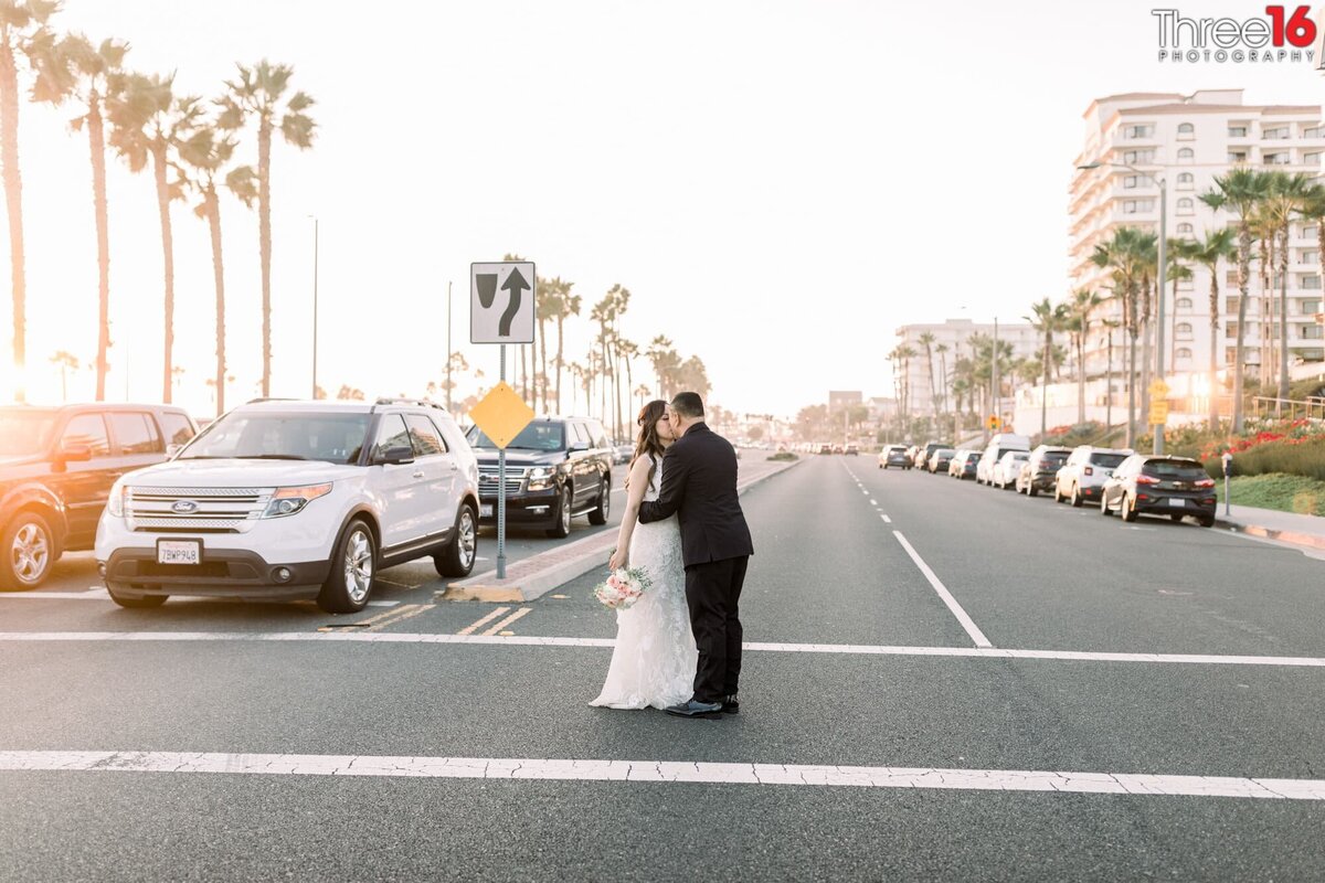 Bride and Groom stop in the crosswalk of a busy street to share a kiss