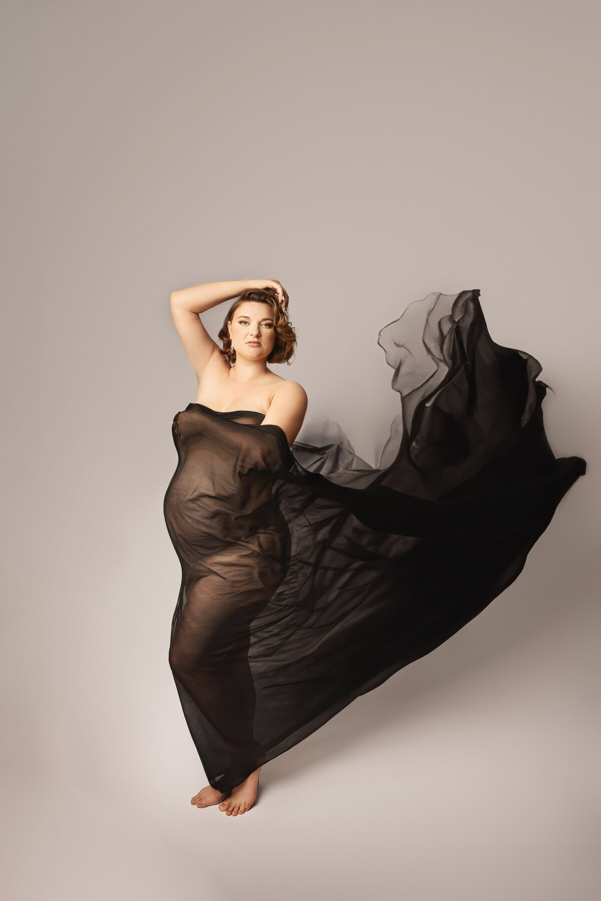 Fine art image of woman with black flowing fabric against white background