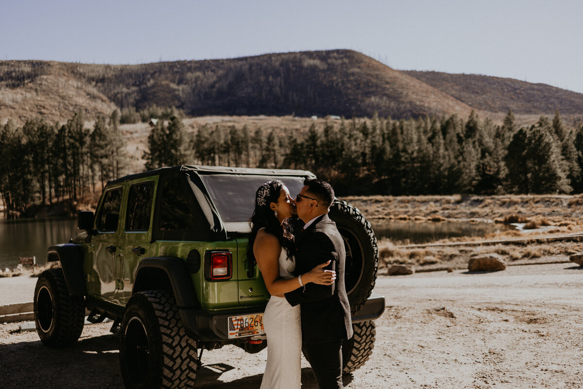 bride adn groom having a first look around the sides of their jeep wrangler