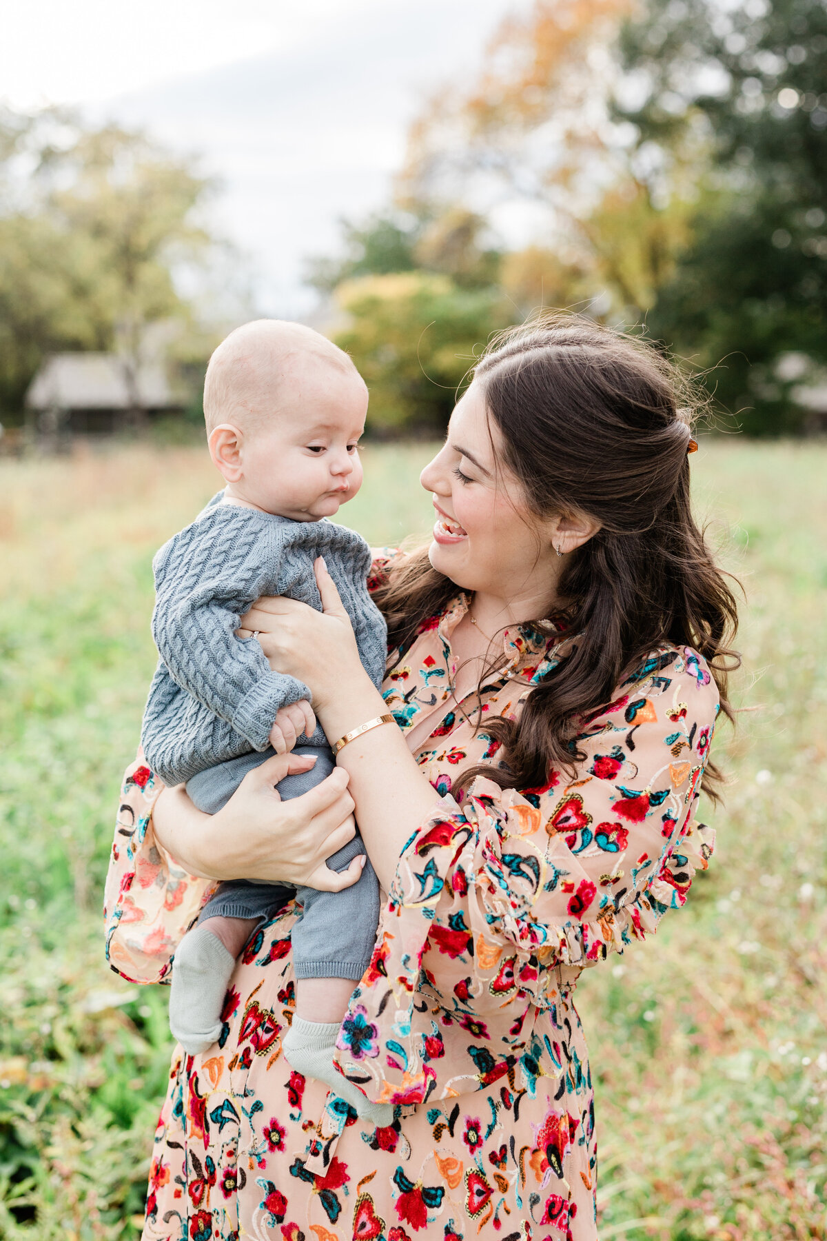 Mom wearing bright floral dress holding infant son