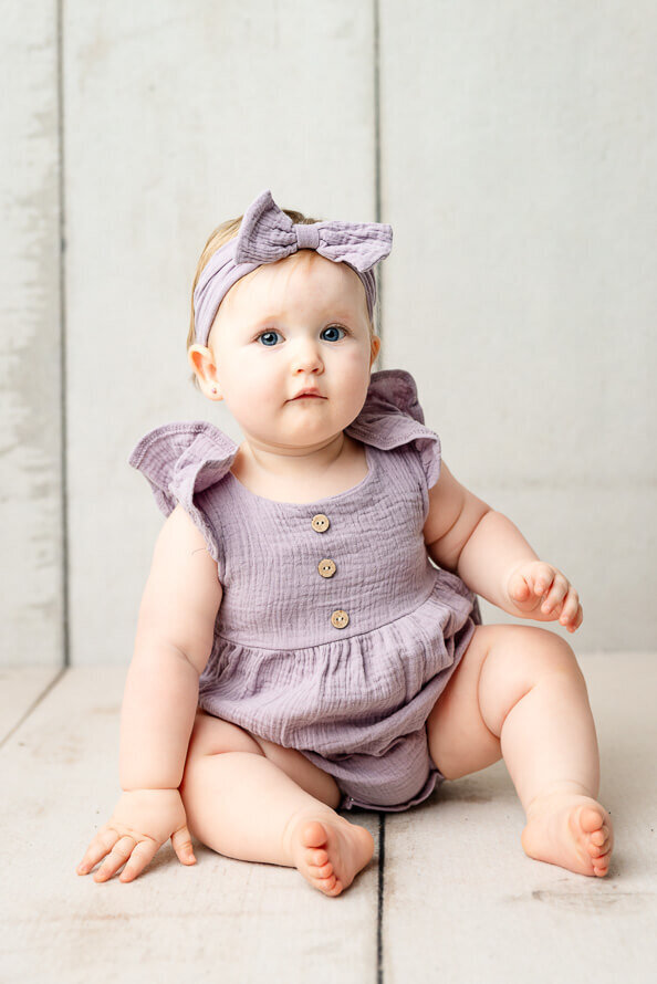 One year old girl sits in a photo studio.
