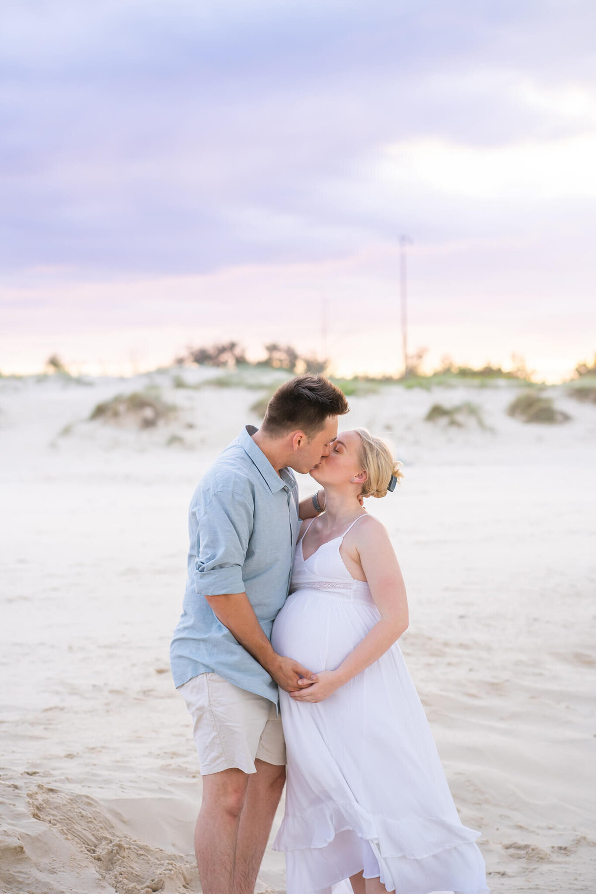 couple kissing in gold coast beach sunset during maternity photoshoot with hikari, gold coast maternity photographer.