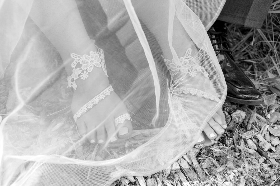 Black and white bride and groom with feet and shoes showing through bridal veil.