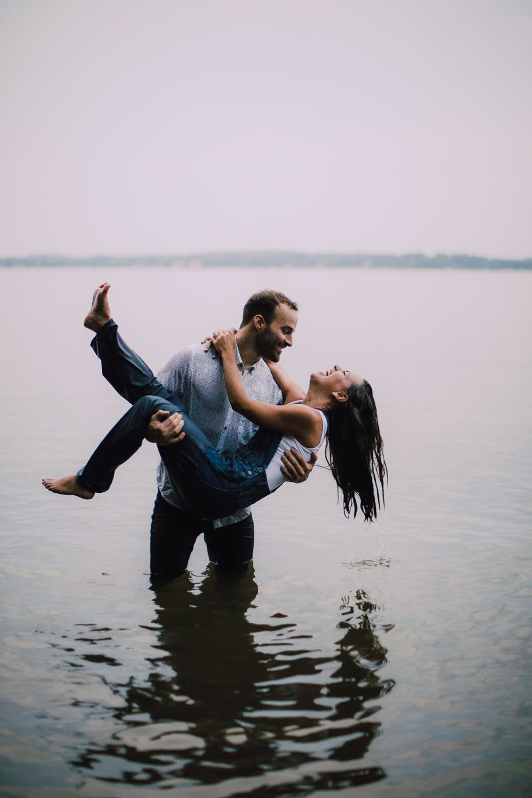 Man holds woman in arms as he dips her into the water
