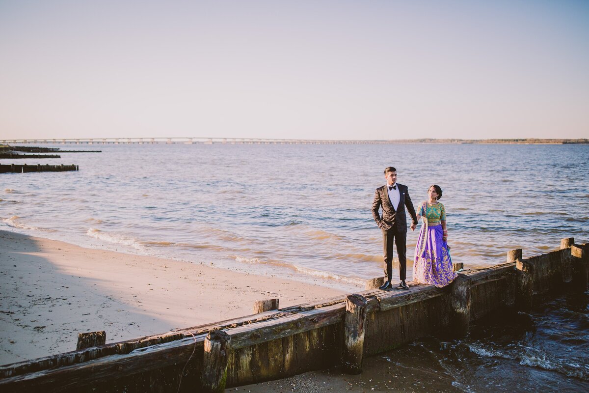 Indian bride and groom walking along a jetty groin during their wedding reception at hyatt cheseapeake bay in maryland