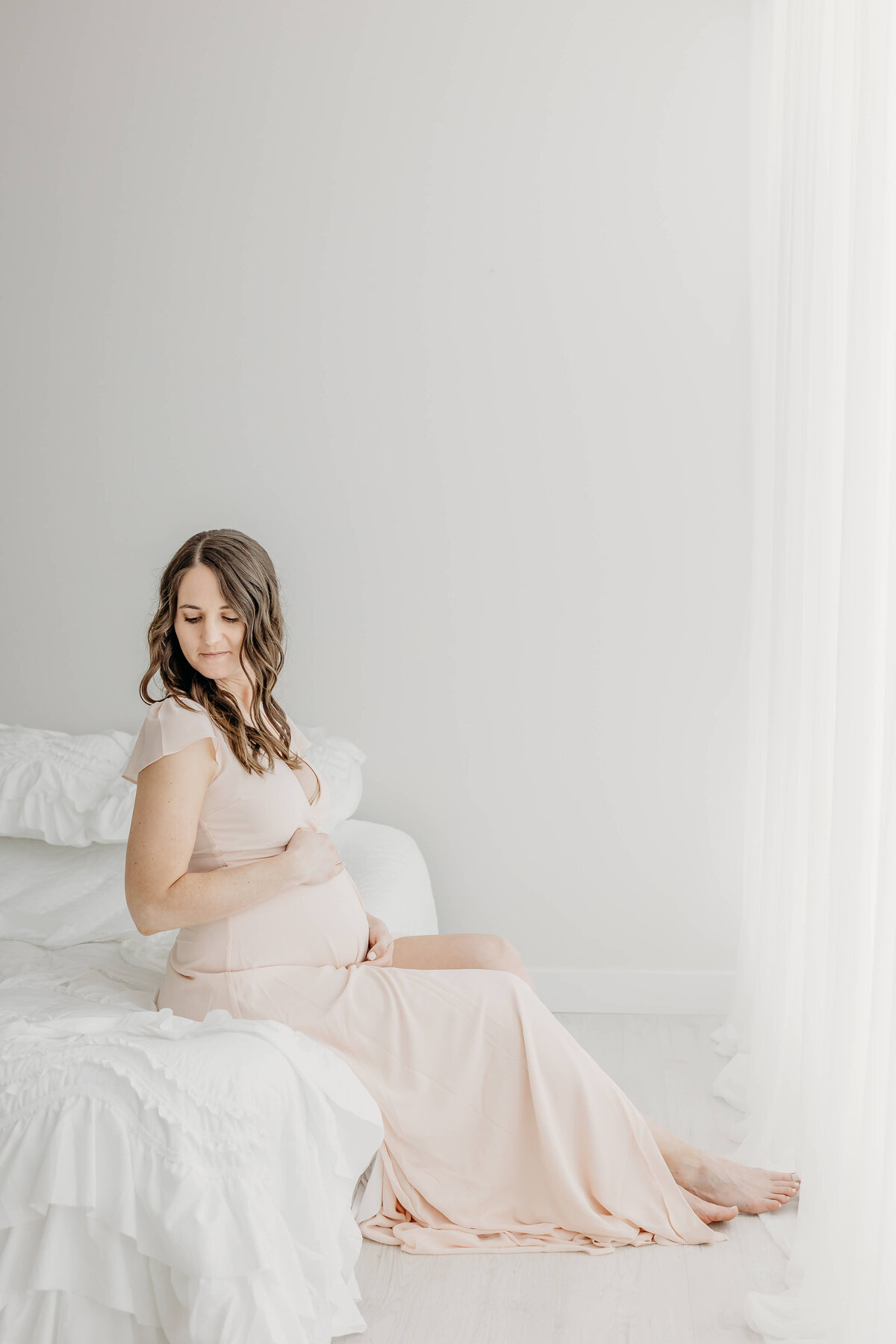 Light pink gown worn by expecting mother in front of window