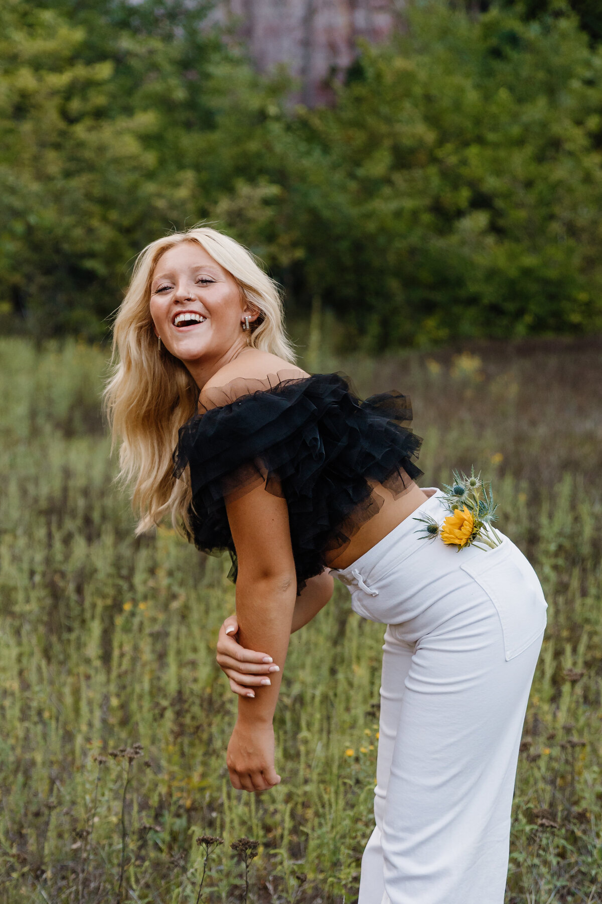 A girl standing in a field with flowers in her back pocket