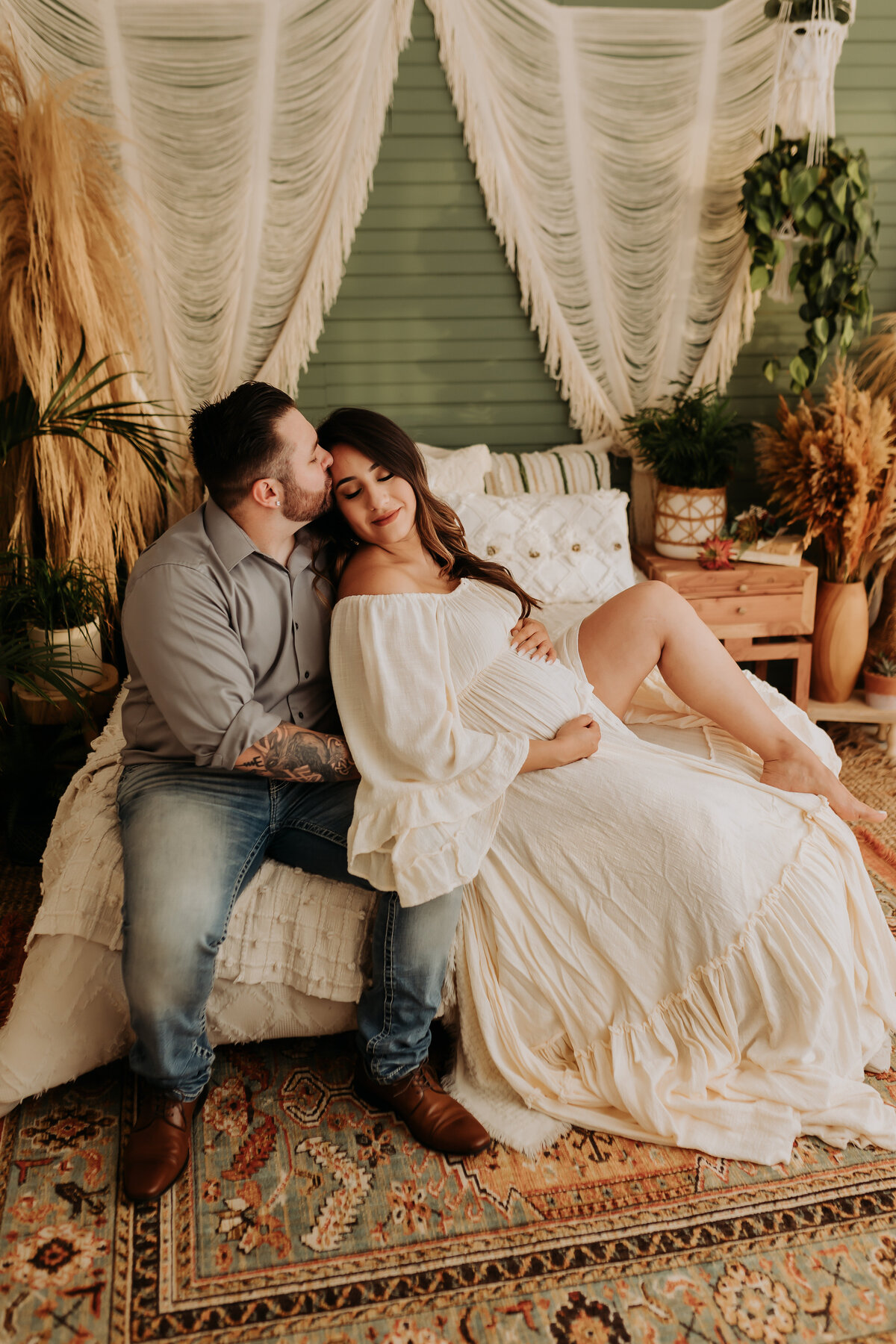 expecting mother wearing white bohemian dress leaning against her partner