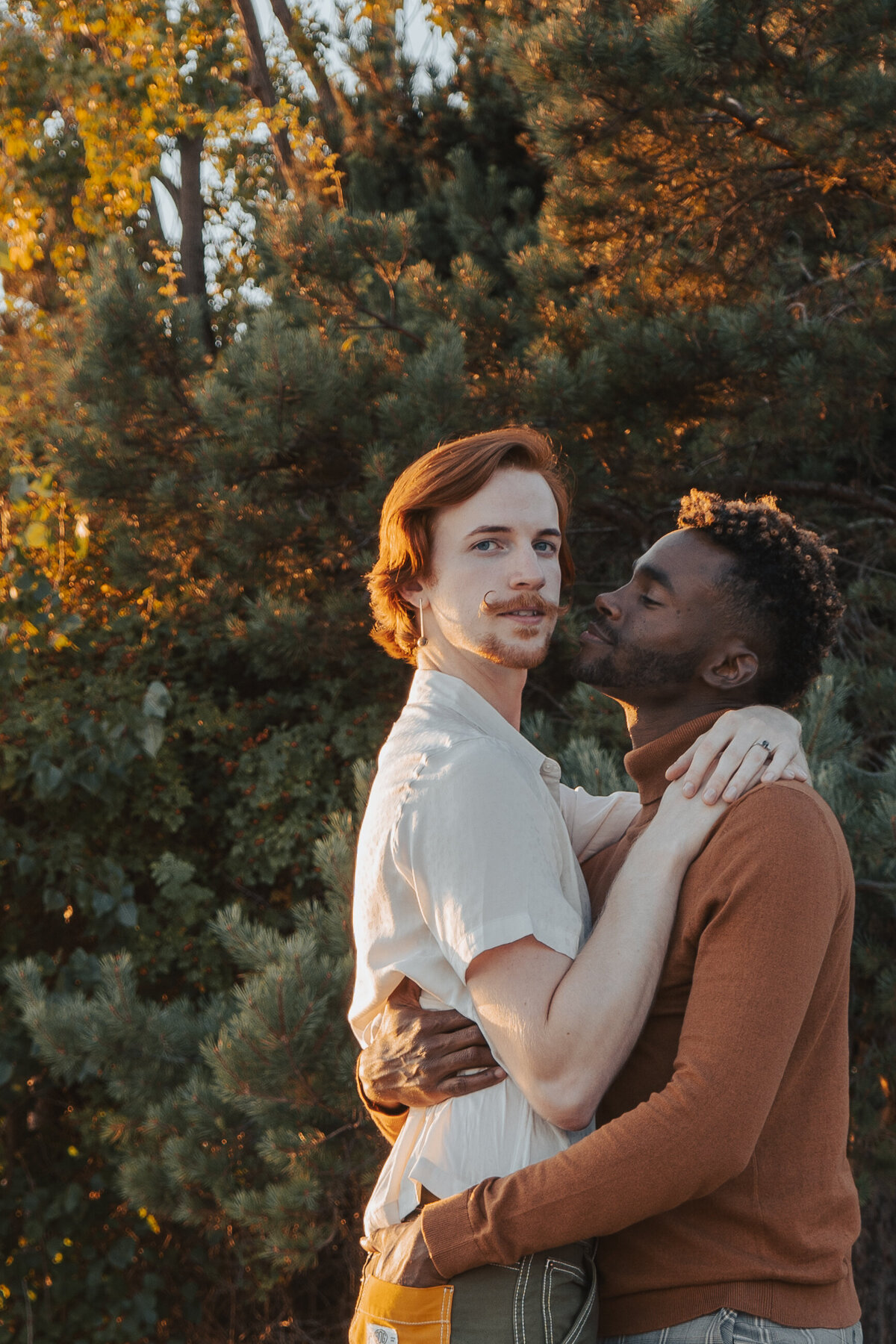 Closeup portrait of queer couple at golden hour in Pocket Beach, Seattle holding each other close as the light reflects off their hair
