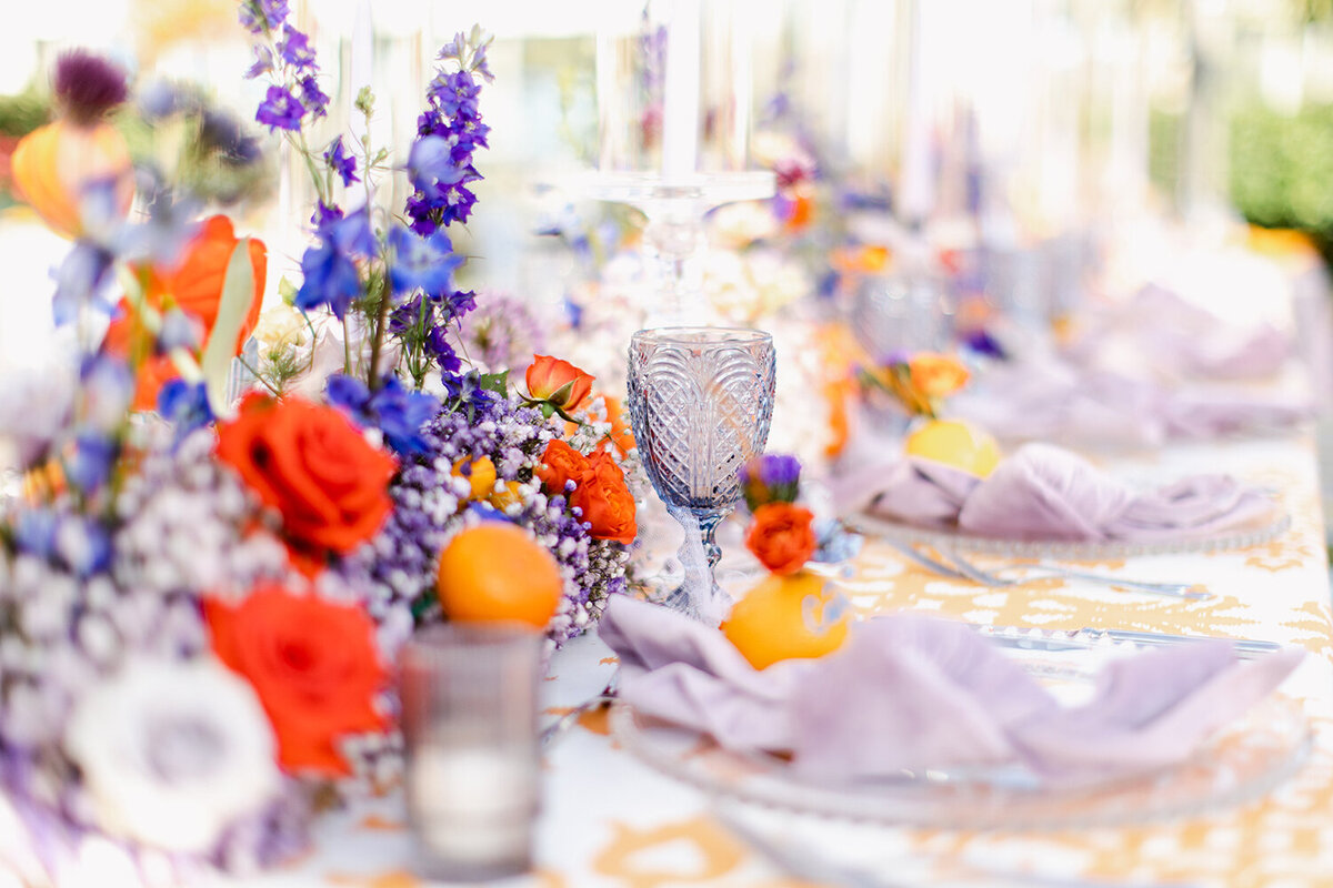 Glass sits on a table surrounded by colorful flowers.