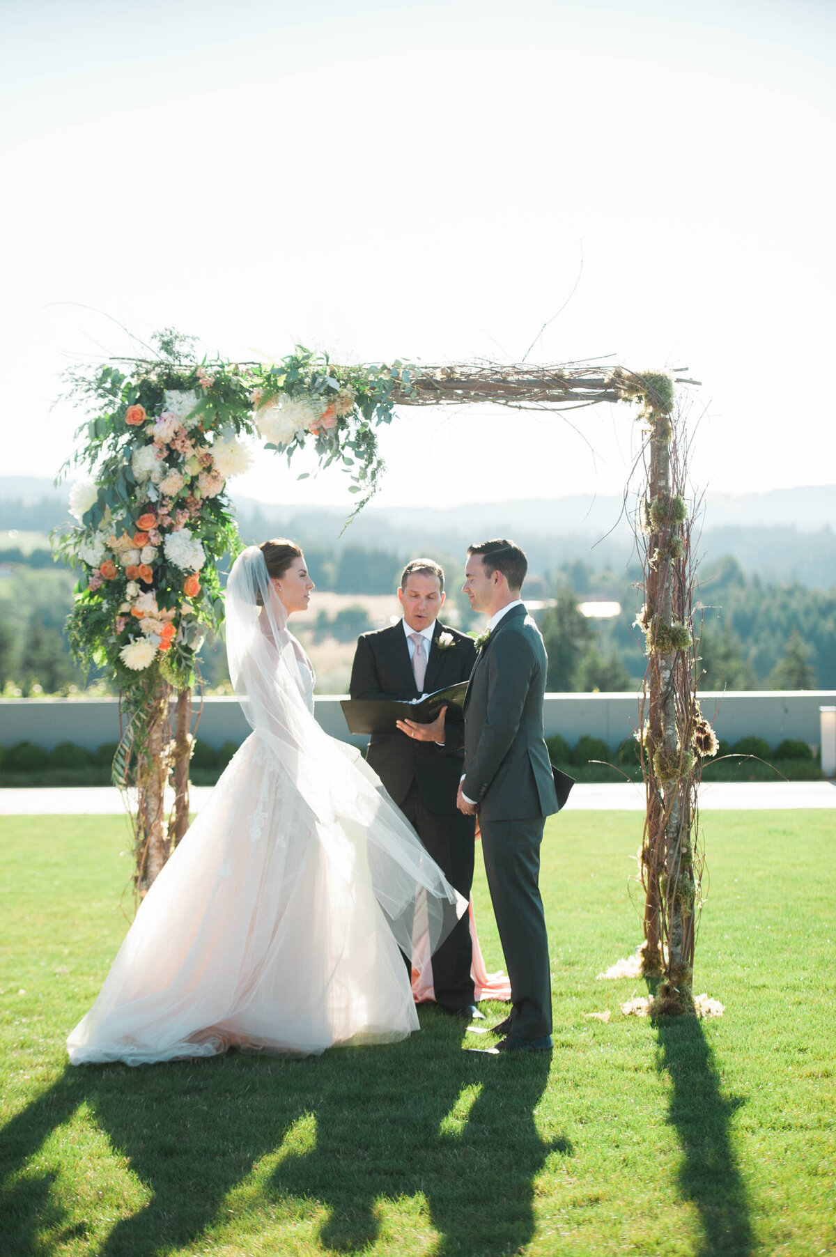 luxury bride and groom under floral arbor at ponzi winery