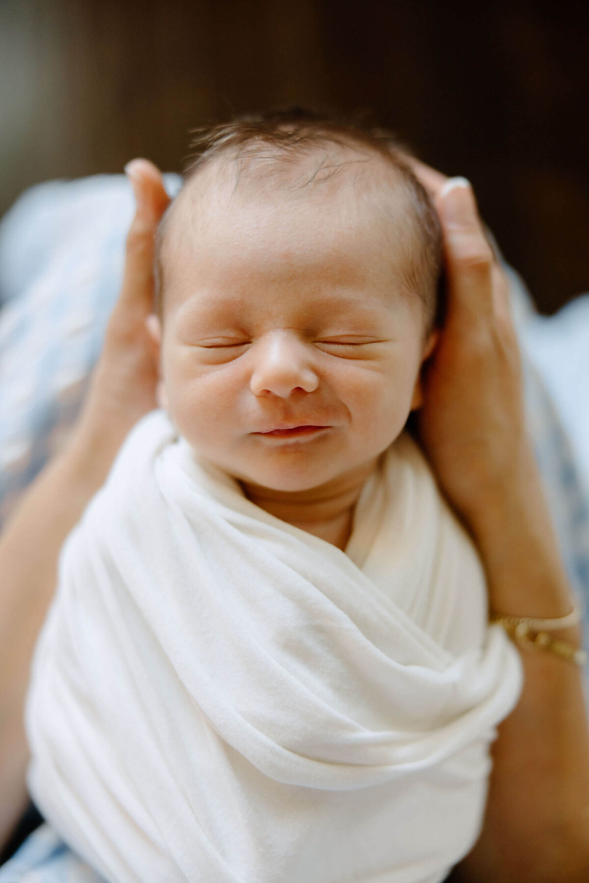 newborn smiling while in mother's hands