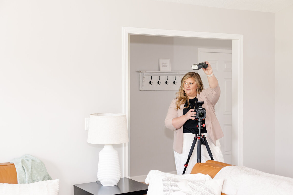 A behind-the-scenes shot of Meg Williamson capturing a living room with professional equipment, including a tripod, camera, and lighting setup. The image highlights her attention to detail and commitment to producing high-quality real estate photography.