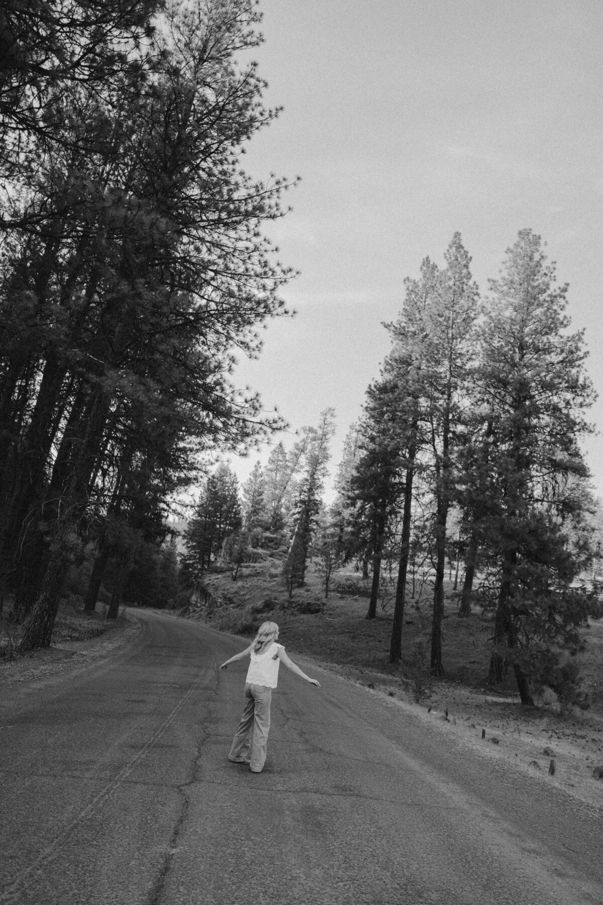 Golden Hour Senior Portrait of Girl Sitting on Log in Floral Dress with Mountain Views
